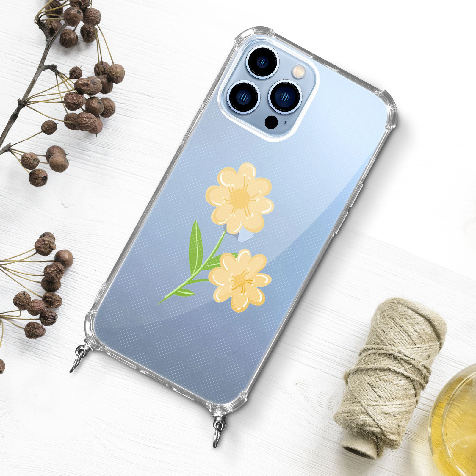 Una custodia trasparente per telefono con un design a fiori gialli è su una superficie bianca. Nelle vicinanze c'è una piccola spoletta di spago.