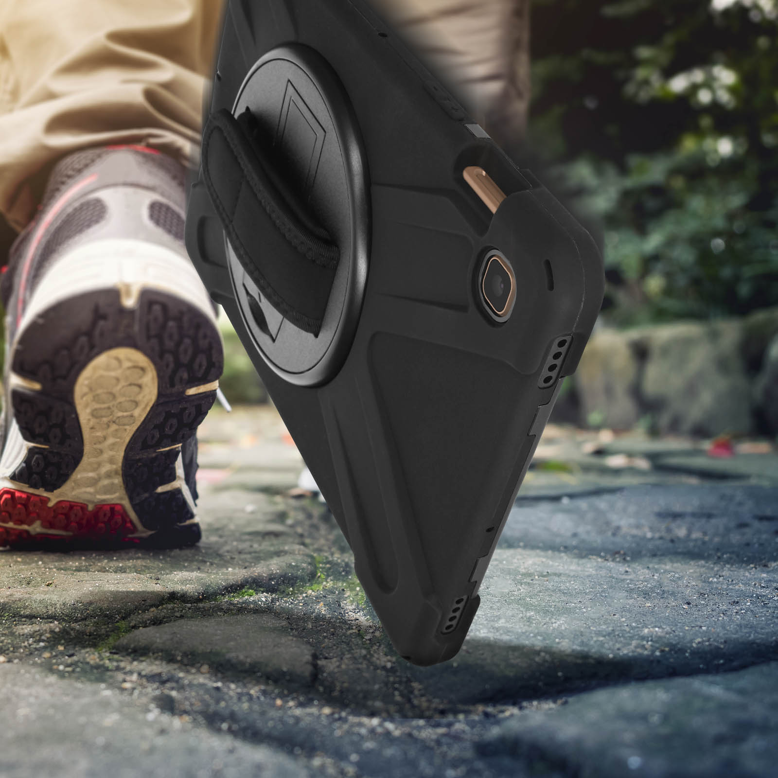 Eine schwarze Handyhülle liegt auf einem gepflasterten Weg. Ein Fuß mit Laufschuh ist sichtbar. Unscharfer Hintergrund.