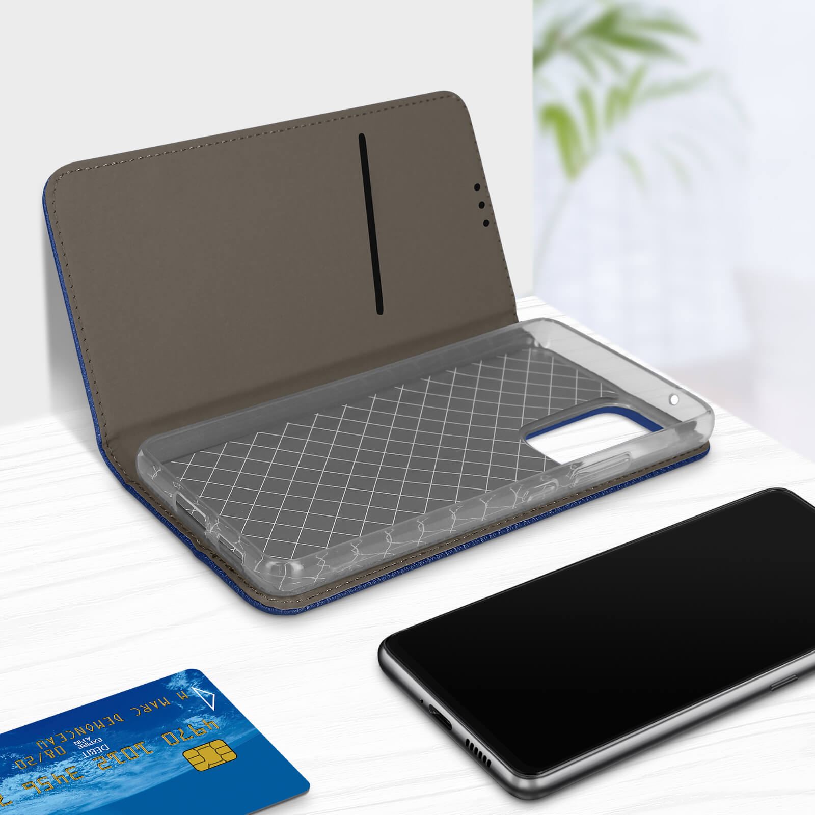 Étui de téléphone bleu et marron ouvert avec un téléphone à l'intérieur. Carte de crédit sur un bureau.