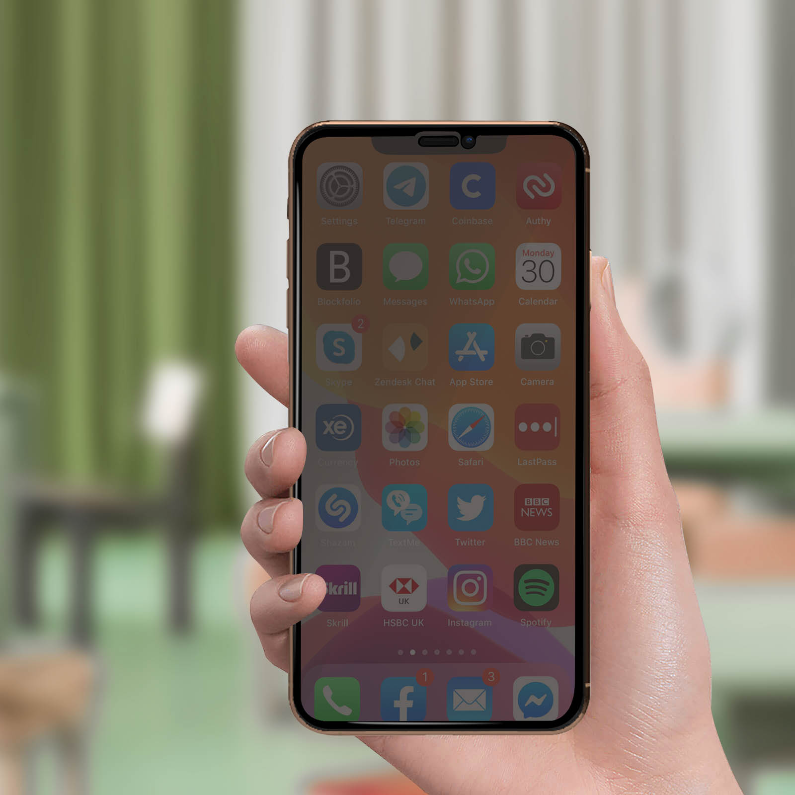 Mano che tiene un telefono con icone di app sullo schermo. Sfondo sfocato.