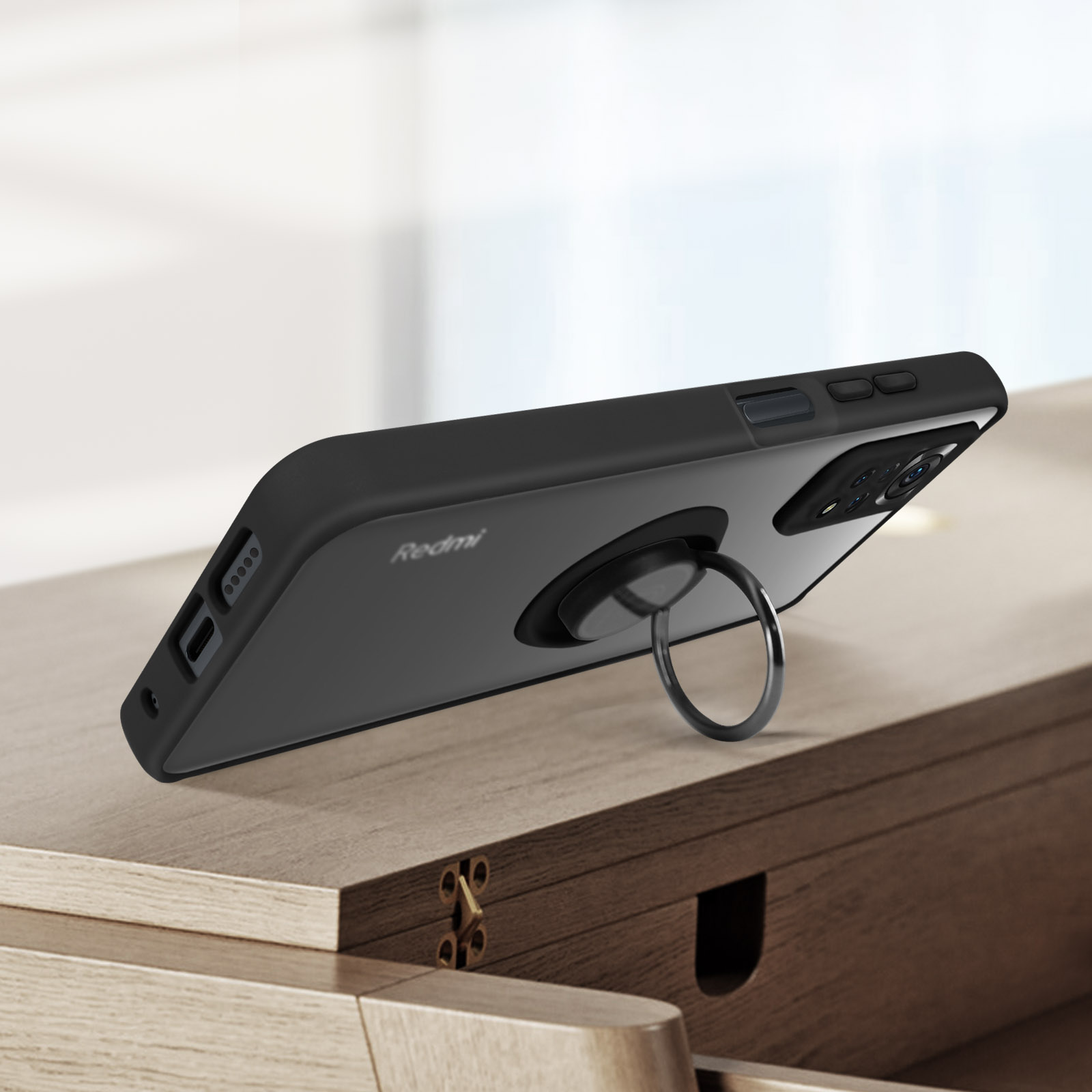 Zwarte telefoonhoes met ringhouder, rustend op een houten oppervlak.