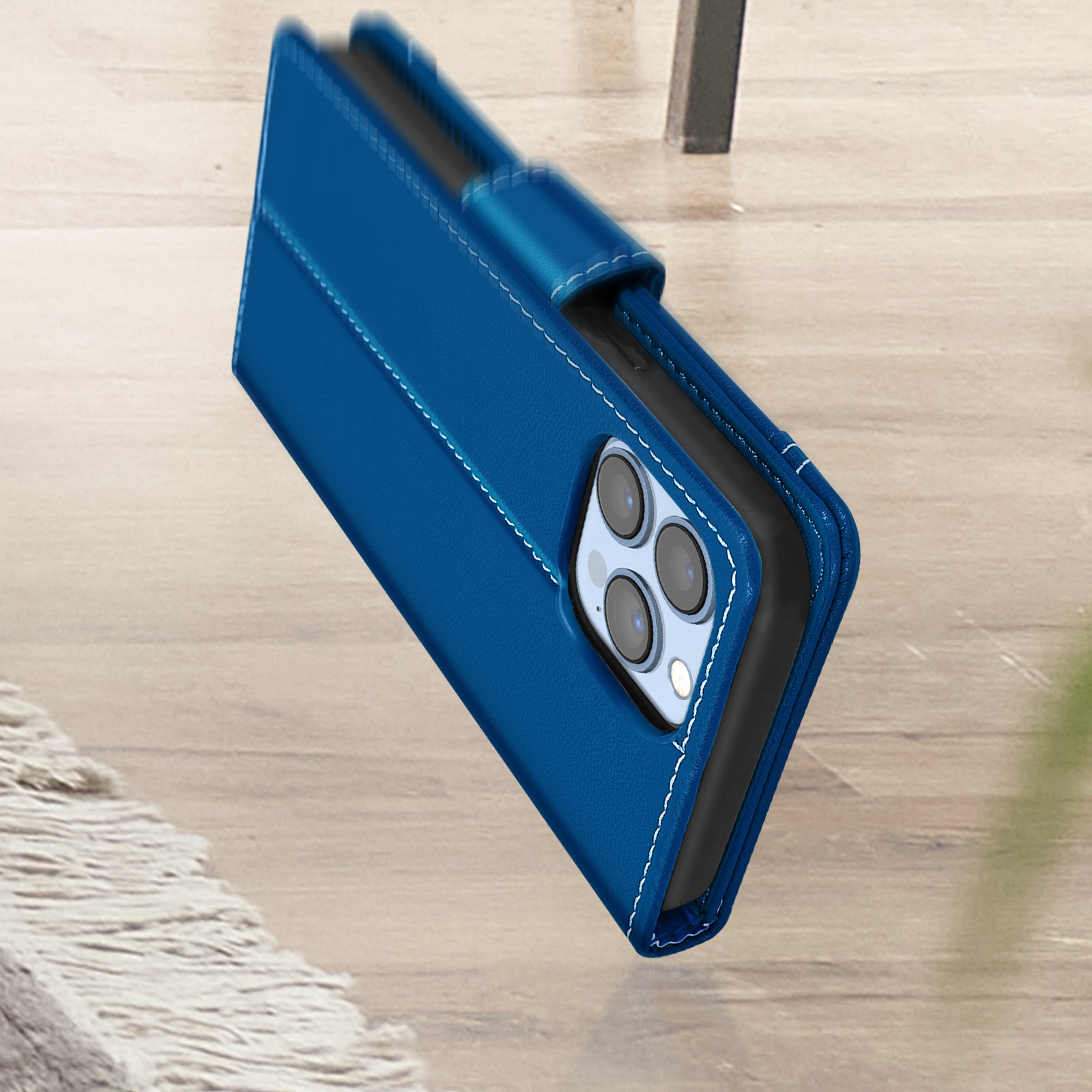 Custodia blu per telefono con cuciture bianche su superficie in legno.