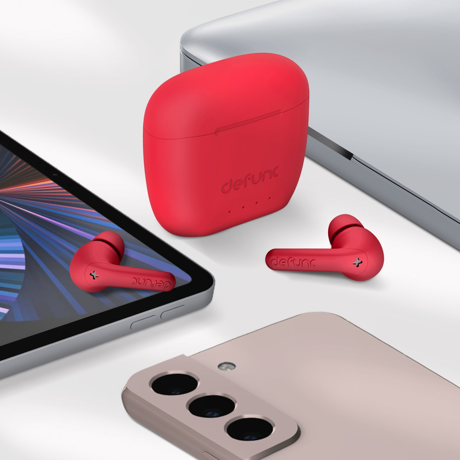 Rote Ohrhörer, Ladecase, Telefon und Tablet auf weißer Oberfläche. Tech-Setup.