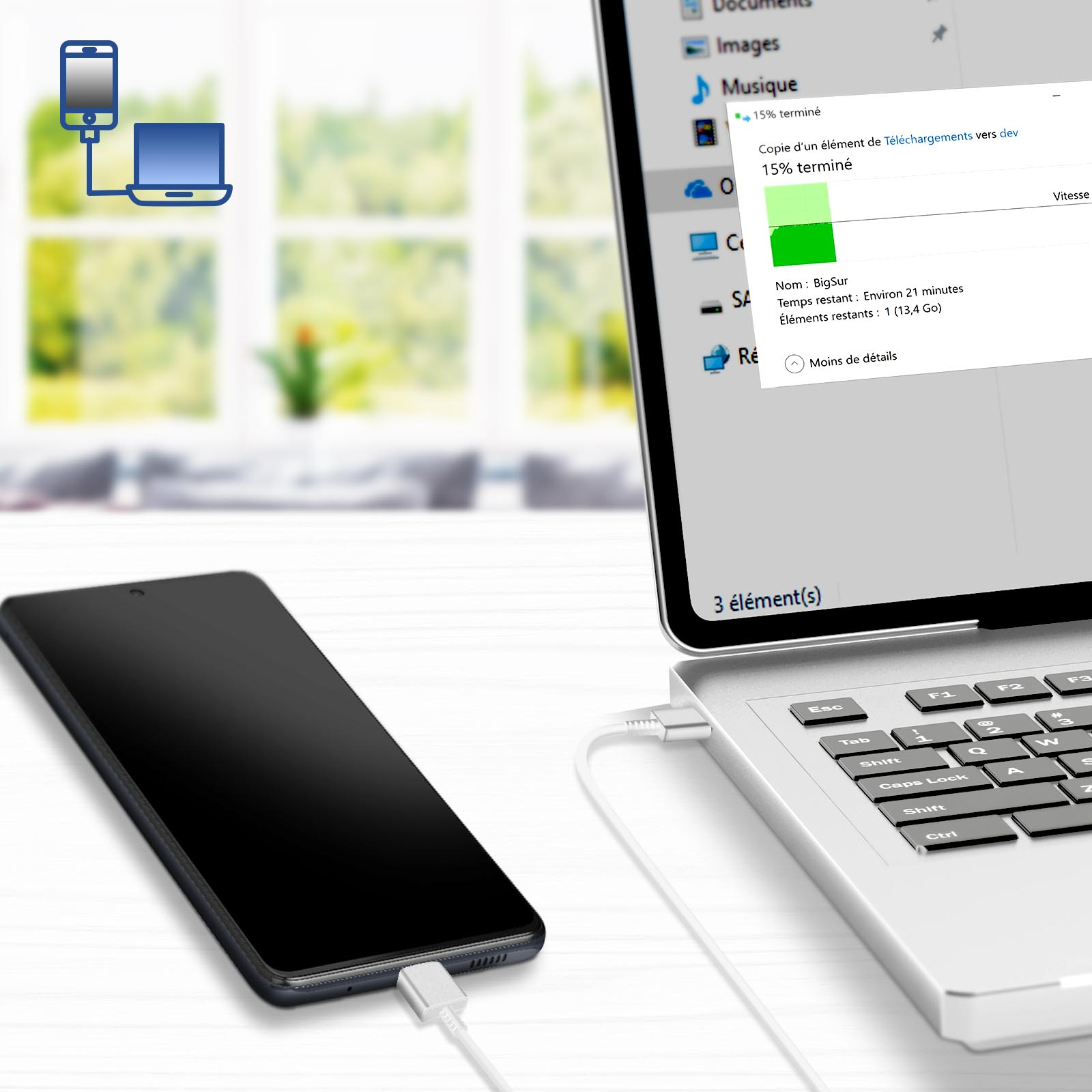 Smartfon połączony z laptopem za pomocą kabla USB. Ekran laptopa pokazuje trwający transfer plików.