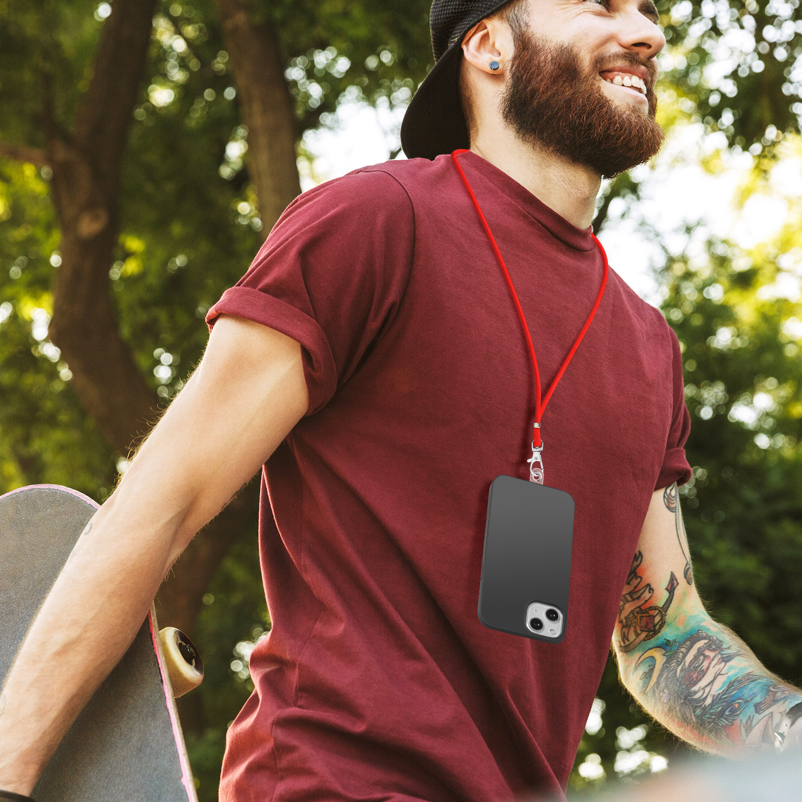 Uomo con barba, maglietta rossa, skateboard e telefono con cordino.
