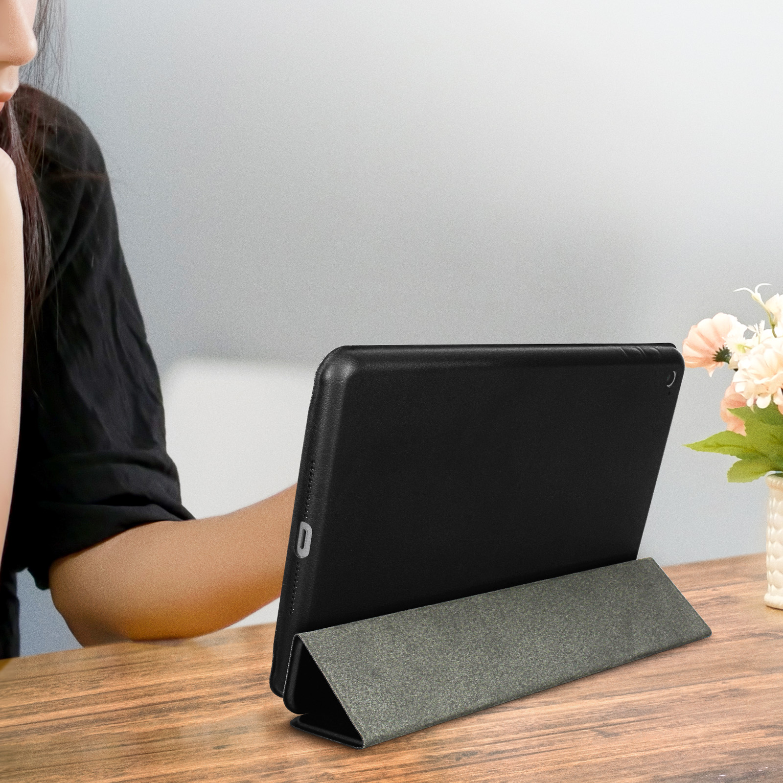 Tablet nero in custodia nera e grigia, appoggiato su un tavolo di legno.