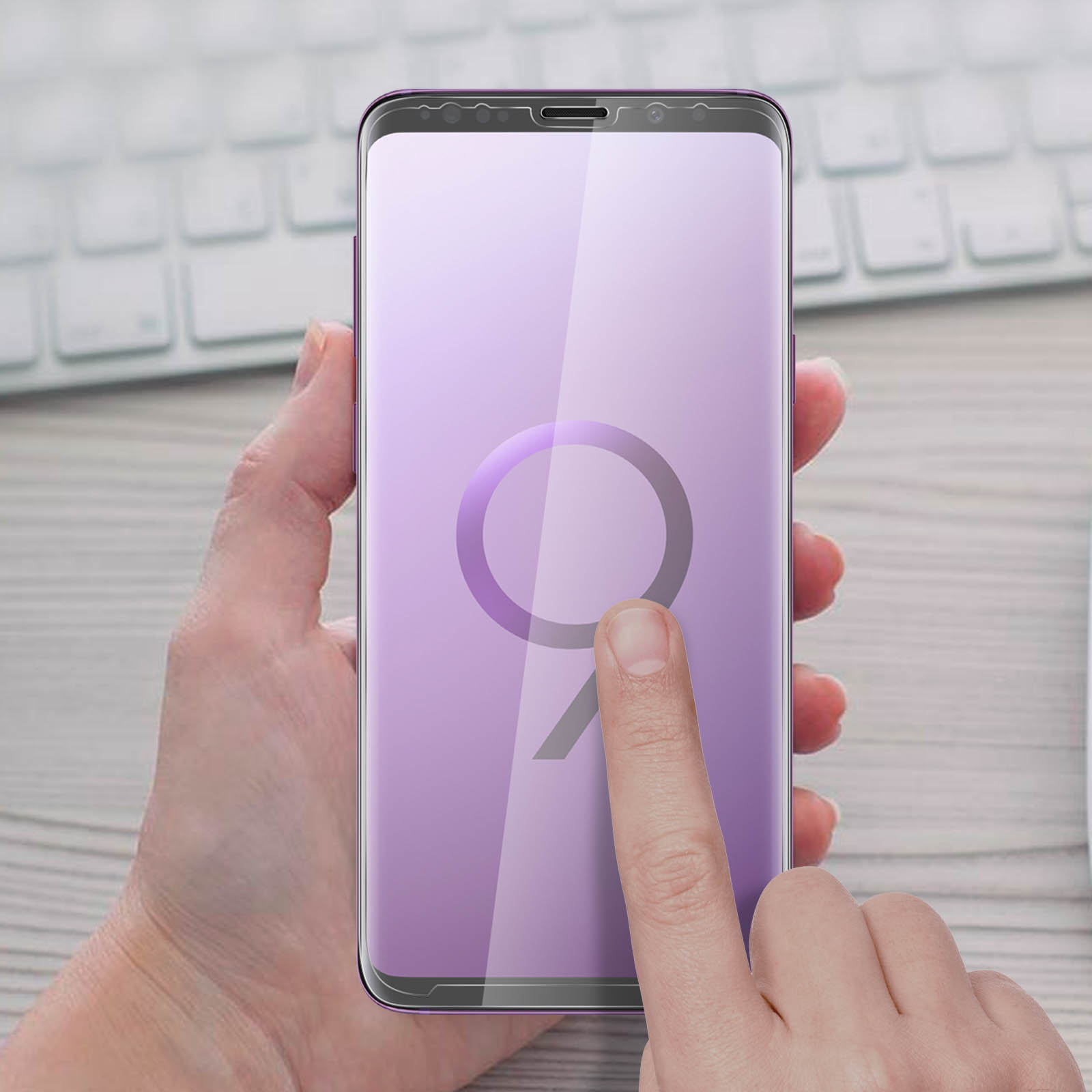 Una mano che tiene un telefono con una protezione per lo schermo applicata. Il telefono mostra il logo 'S9' viola.