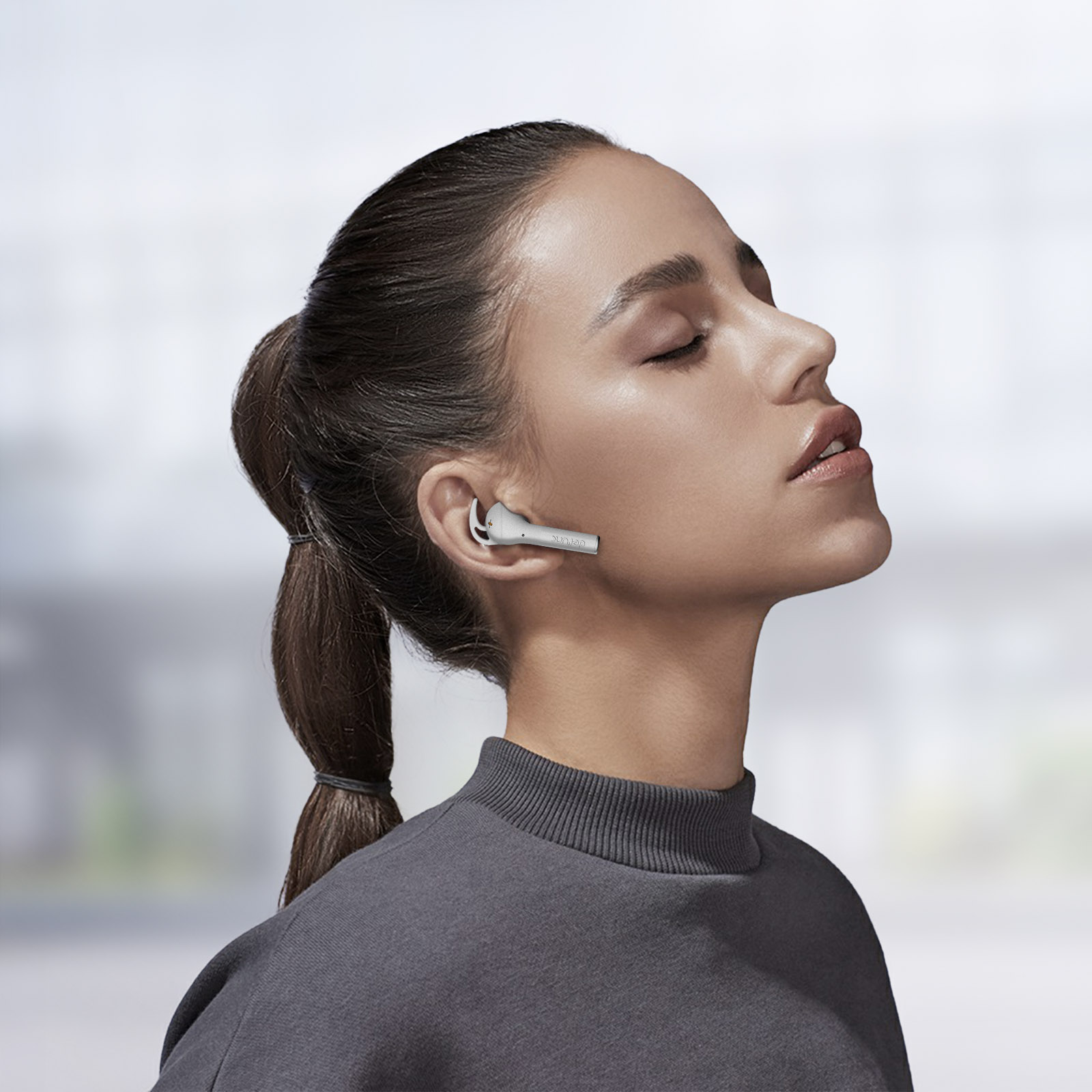 Donna con auricolare wireless. Guarda in alto con gli occhi chiusi.