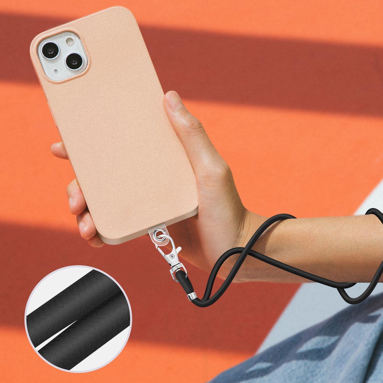 Una mano tiene un iPhone color pesca con un laccetto nero attaccato alla base.