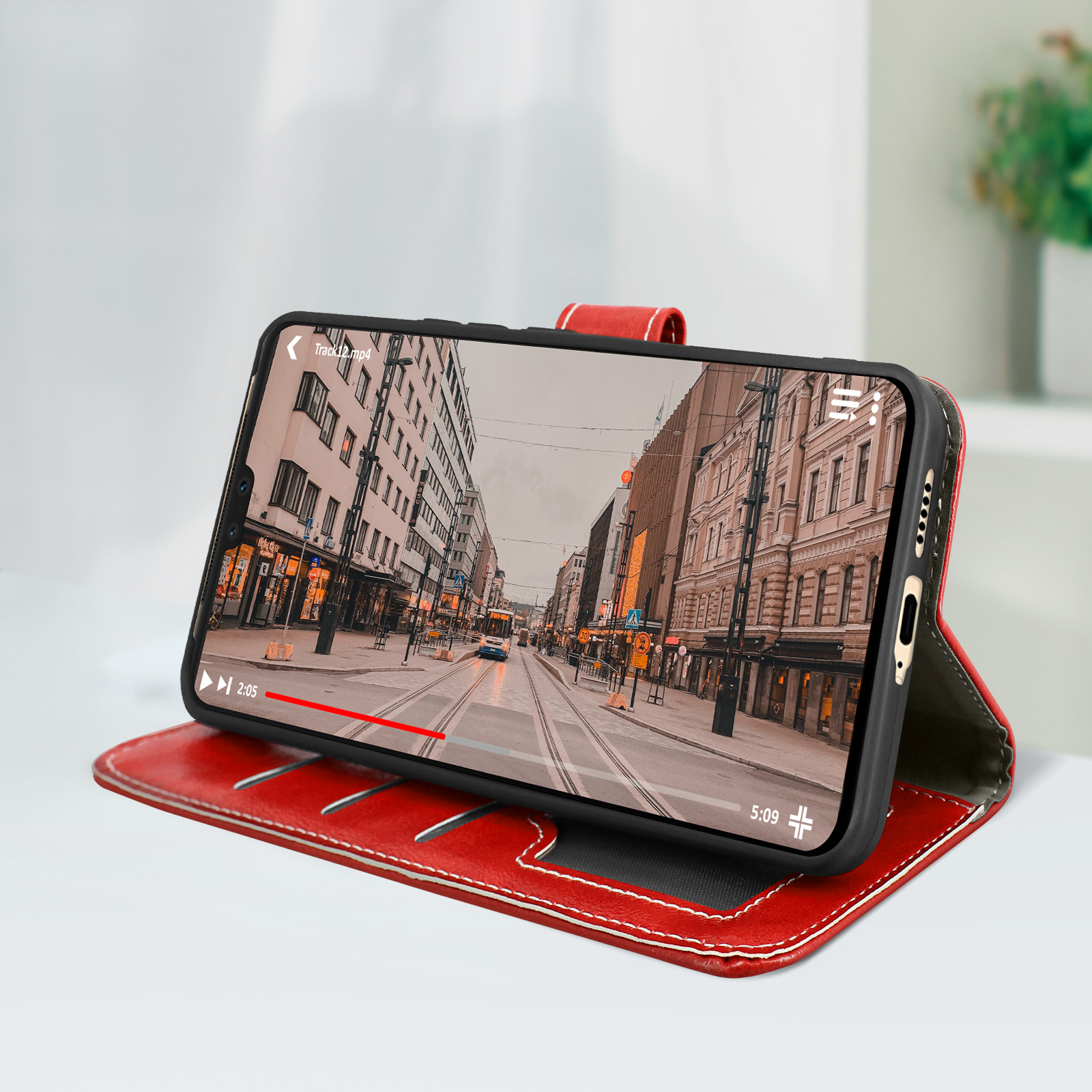 Custodia rossa con telefono che mostra una scena stradale. Aperta su tavolo bianco.
