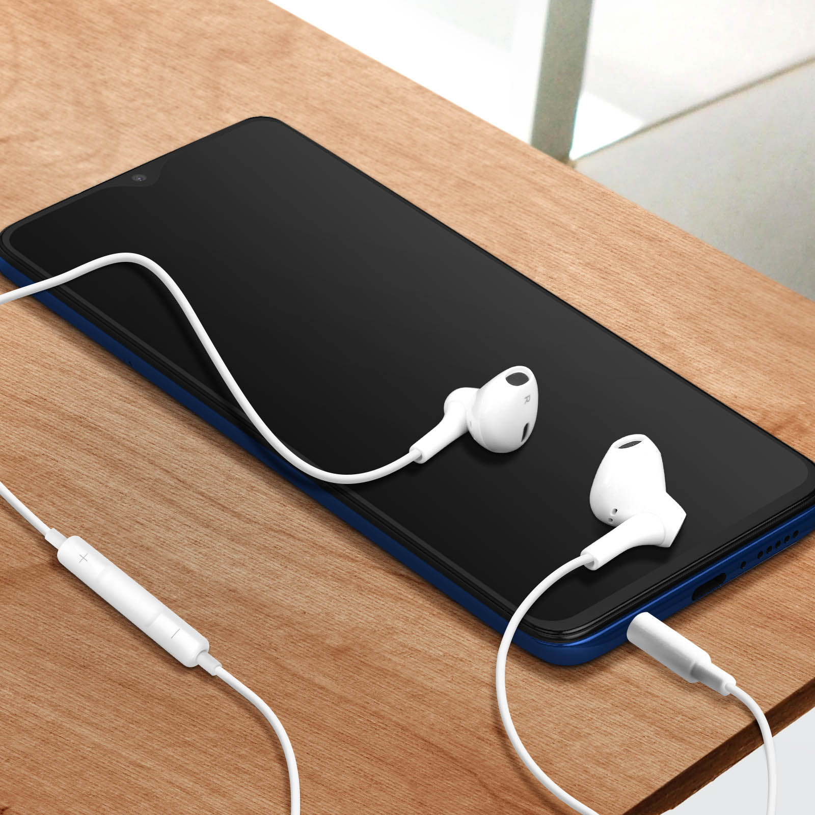 Un teléfono negro con auriculares blancos. Cable blanco. Borde azul en el teléfono. Fondo claro.