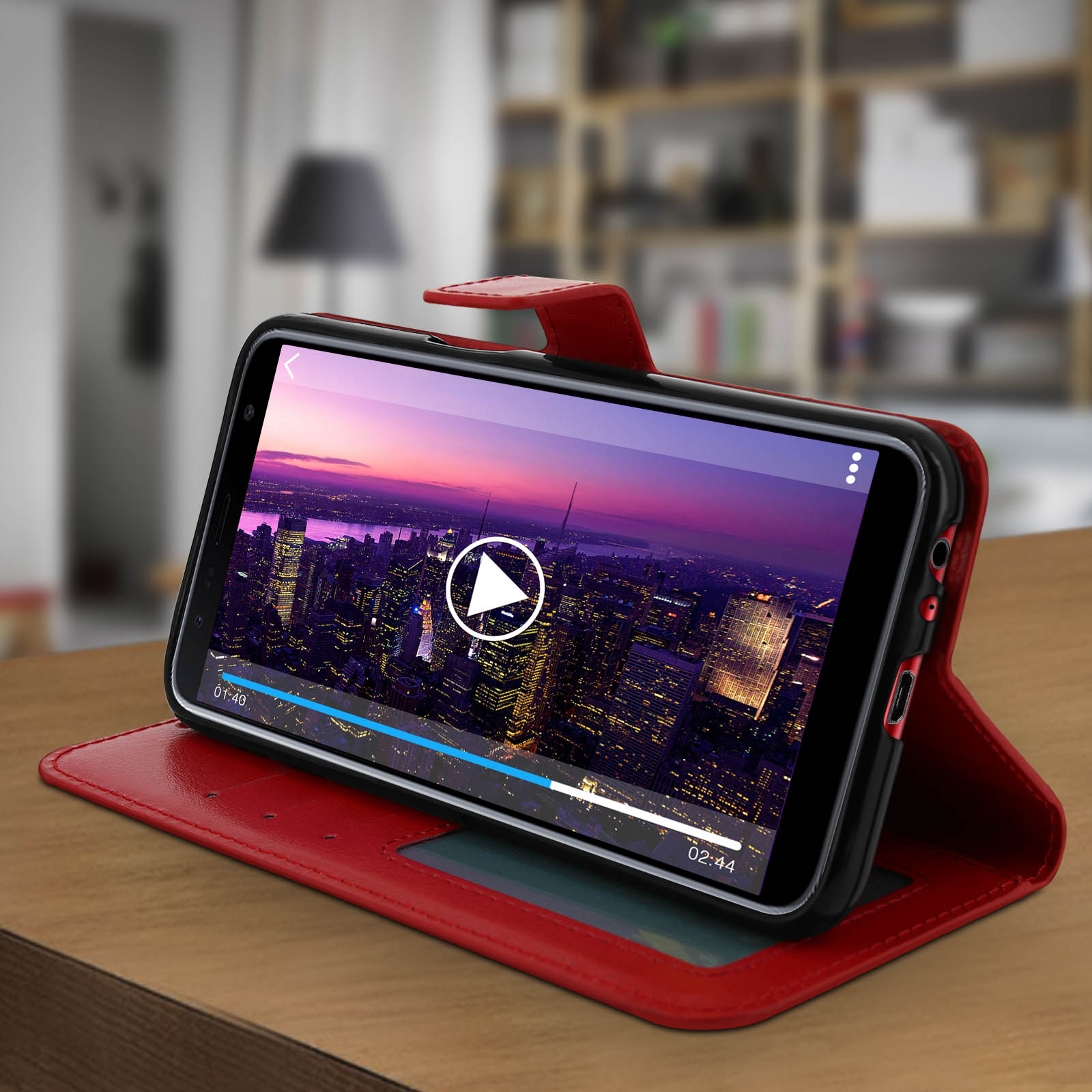 Smartphone in custodia rossa, mostra un video di uno skyline notturno.