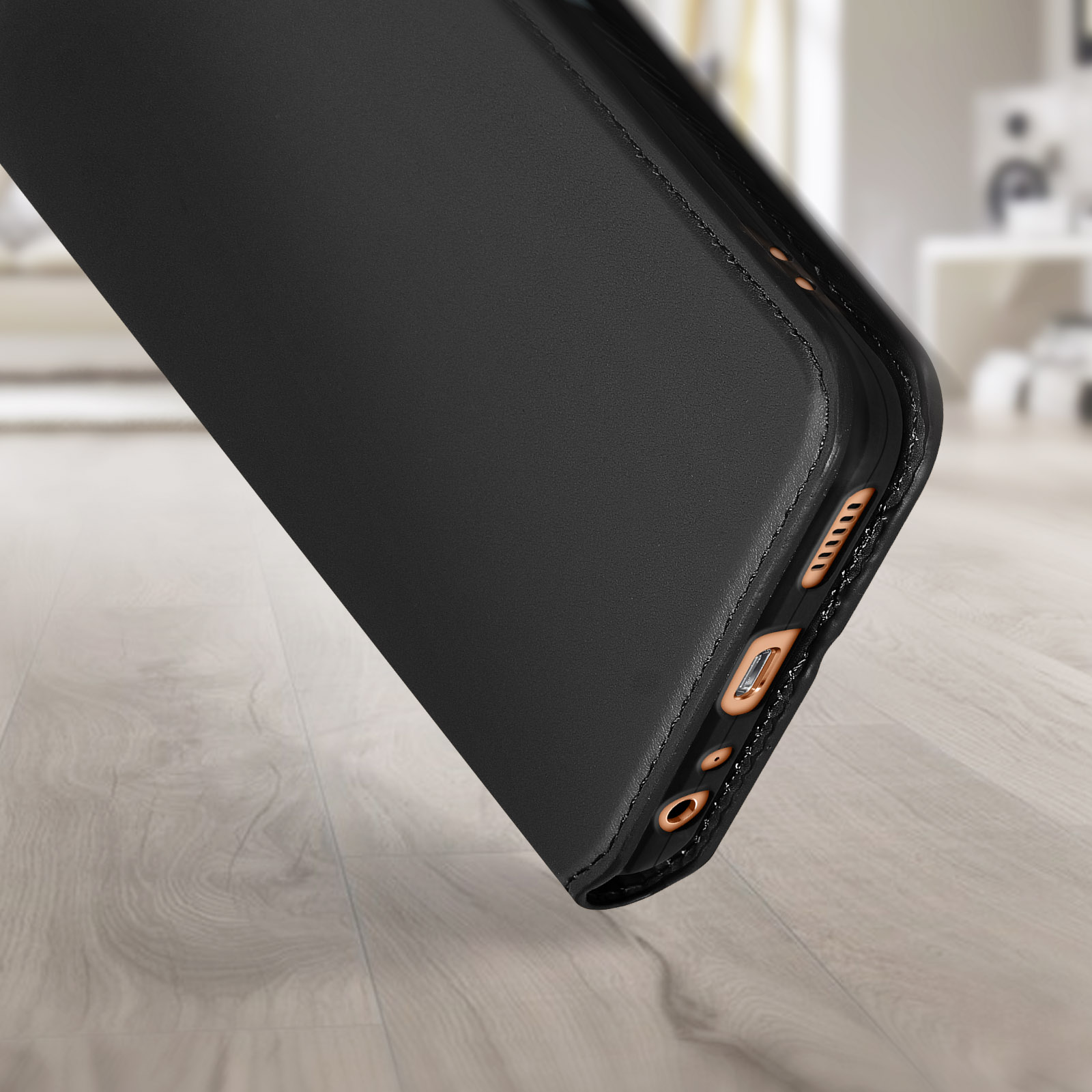 Zwarte telefoonhoes, schuine weergave. Toont de zijkant met poorten en knoppen. Houten vloer.