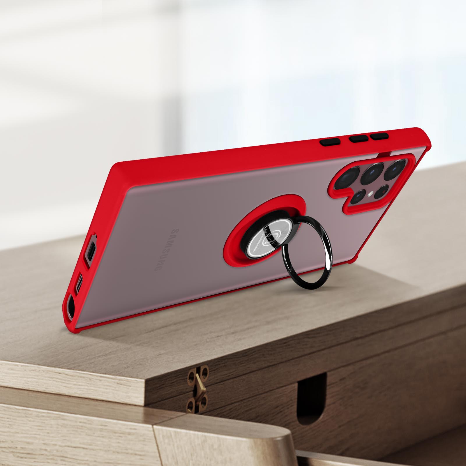 Coque de téléphone rouge avec support de bague. Le téléphone est sur une surface en bois. Le fond est flou.