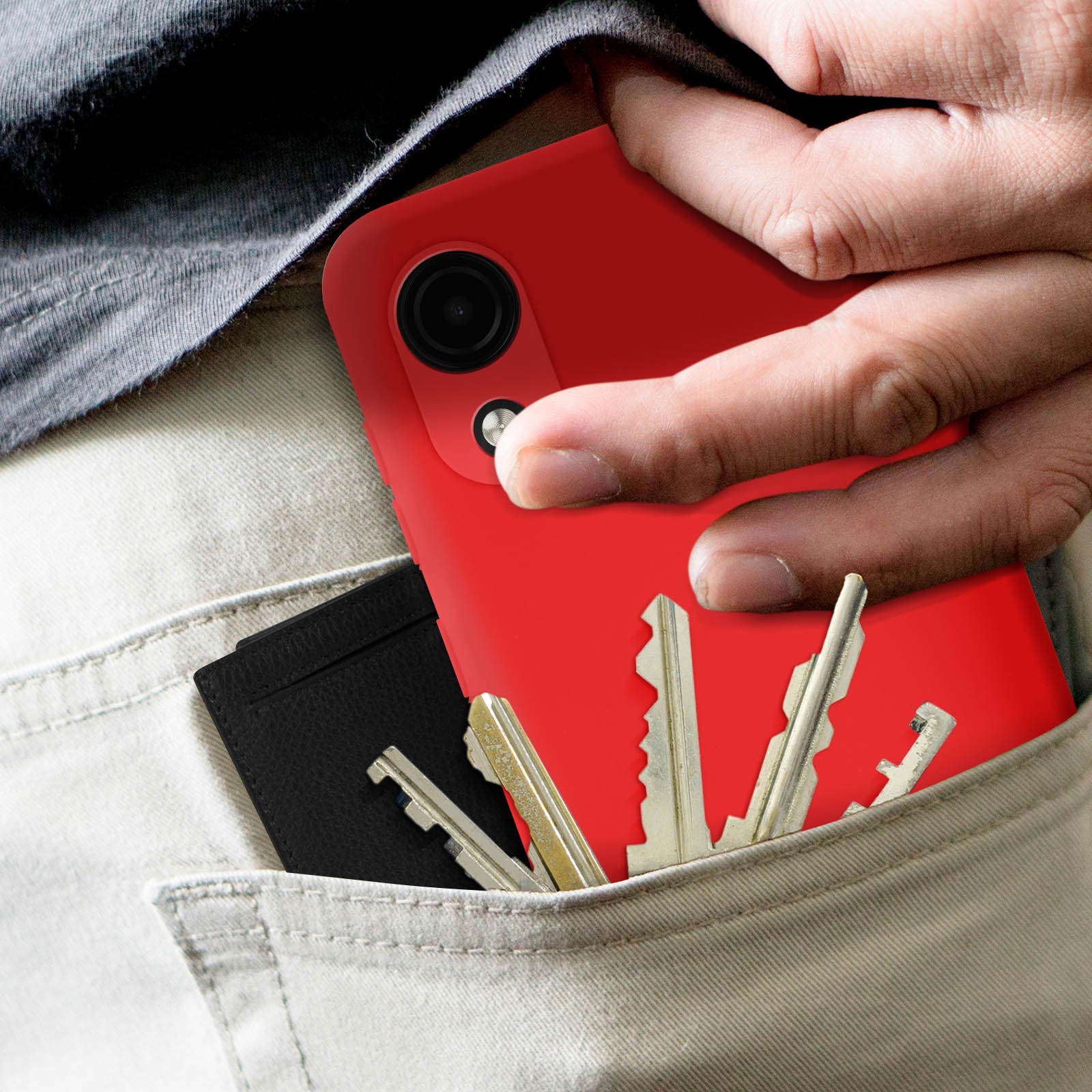 Main avec téléphone rouge dans la poche avec clés et portefeuille. Pantalon clair.