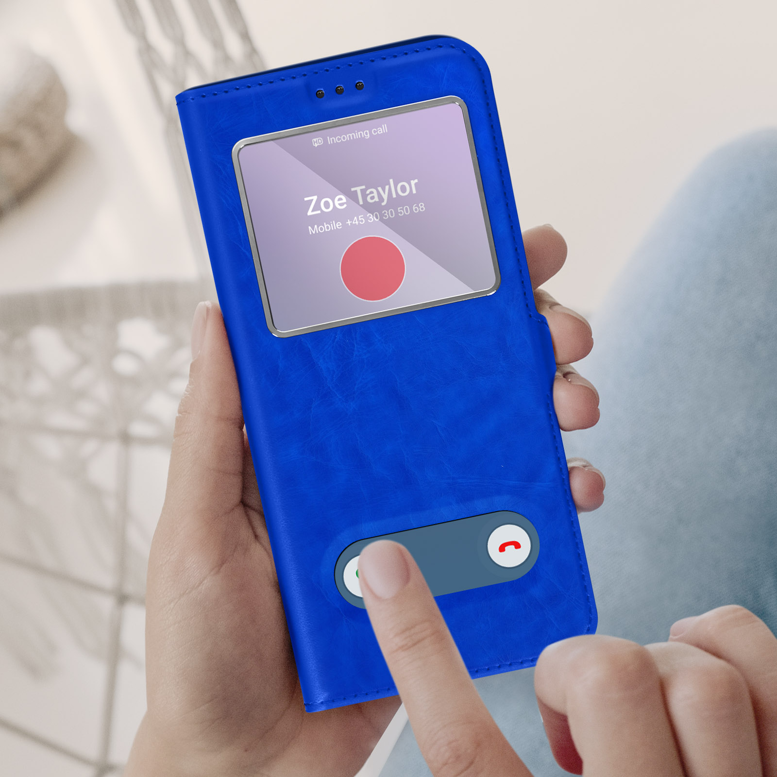 Un téléphone dans un étui bleu affiche un appel entrant. Un doigt appuie sur le bouton de réponse.