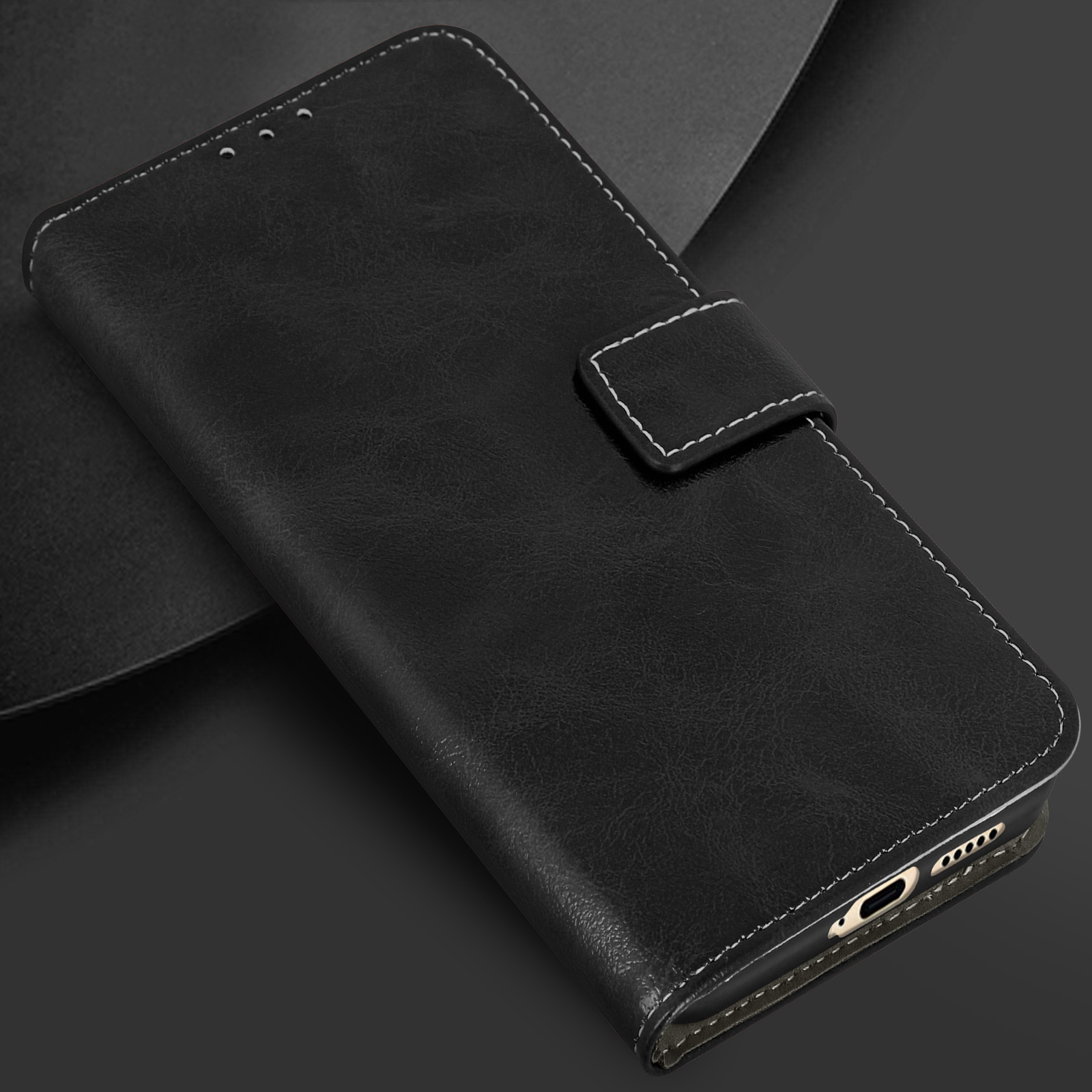 Una custodia per telefono in pelle nera chiusa con cuciture bianche e chiusura magnetica. La custodia è su una superficie scura.
