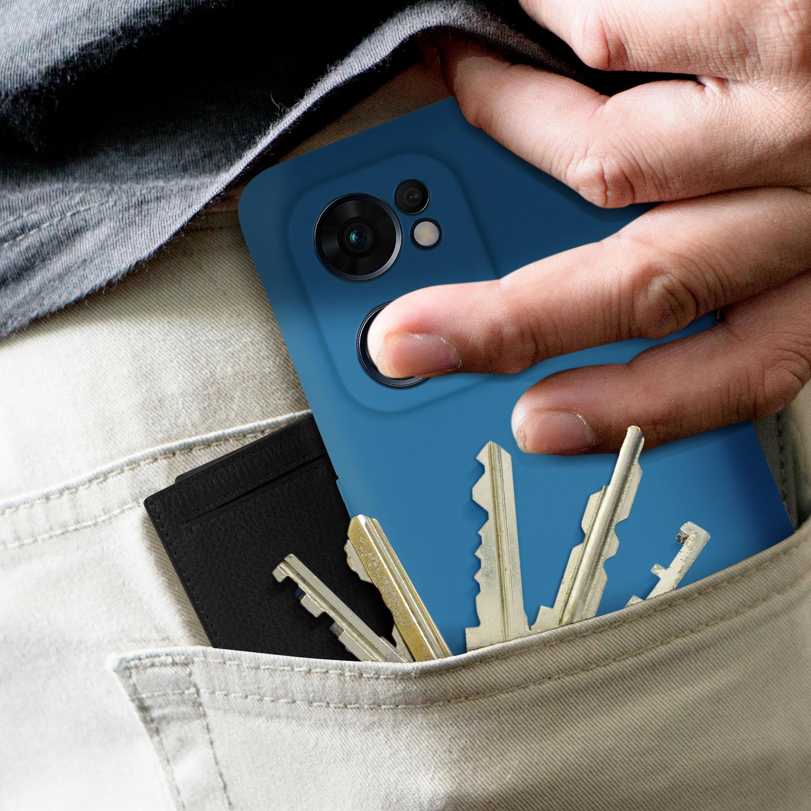 Una mano in tasca tiene chiavi e un telefono in una custodia blu. Un portafoglio poggia nella tasca con il telefono.