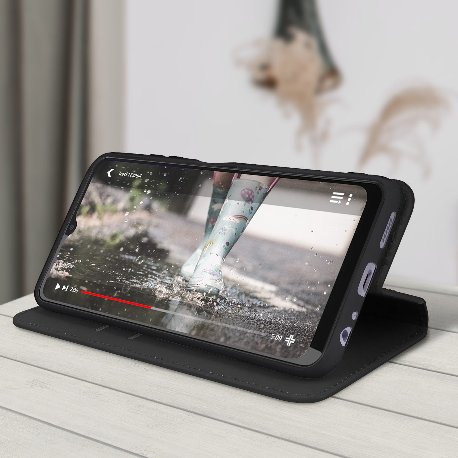 Telefon in einer Hülle, die ein abgespieltes Video zeigt. Tisch mit verschwommenem Hintergrund.