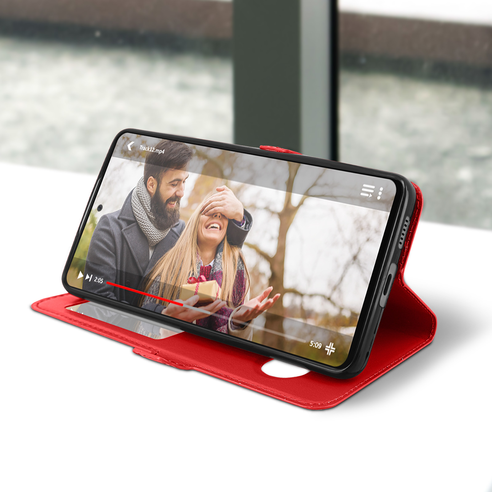 Un téléphone dans un étui rouge affiche une vidéo. Un couple est à l'écran. L'étui est ouvert.