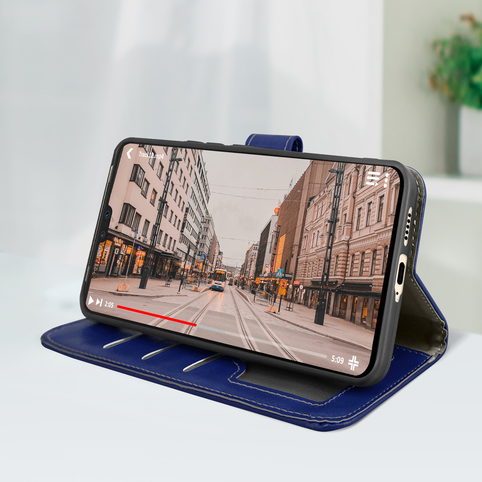 Custodia blu per telefono. Telefono che mostra un video. Su un tavolo bianco, sfondo sfocato.