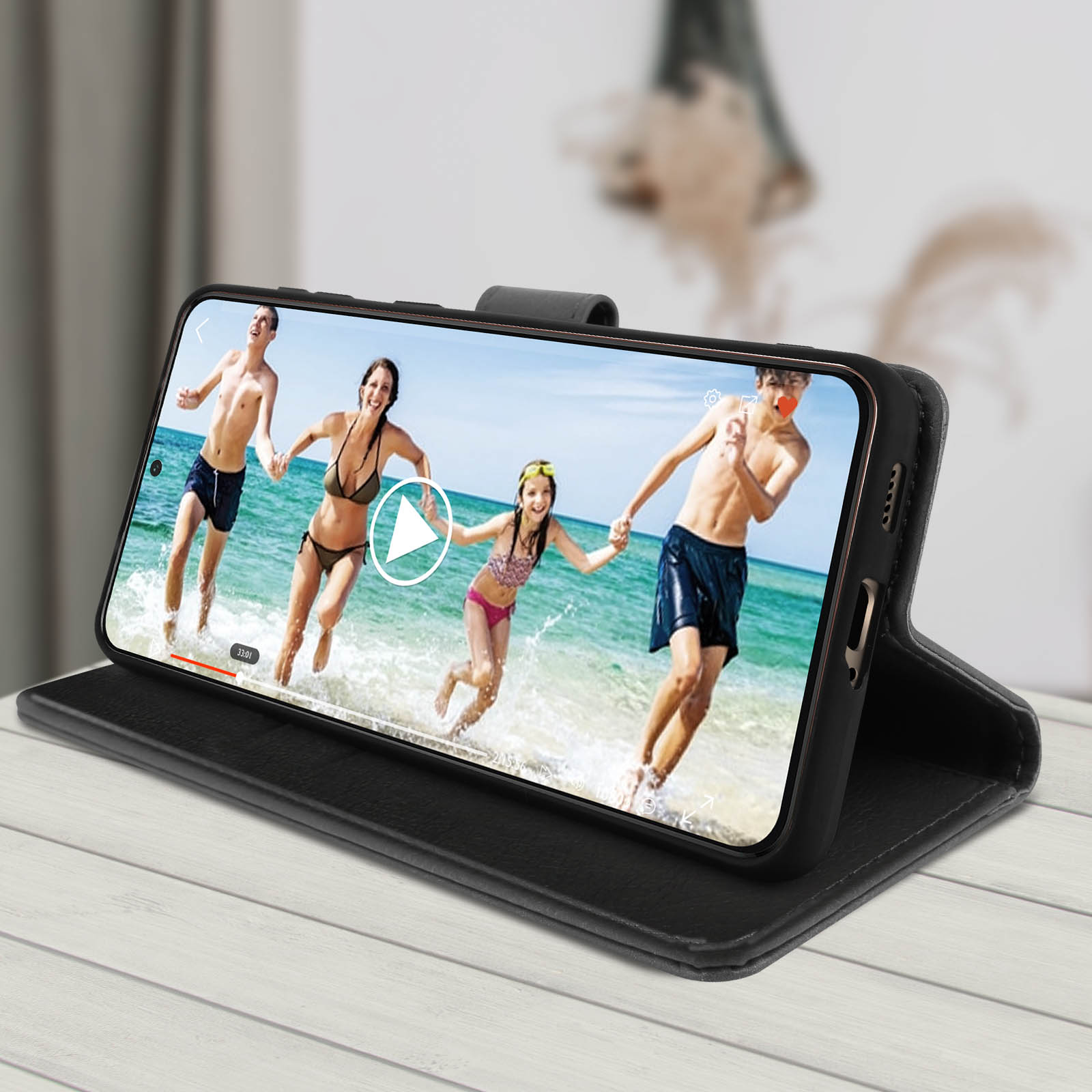 Telefono in custodia nera che mostra un video di persone in acqua. Sfondo in legno.