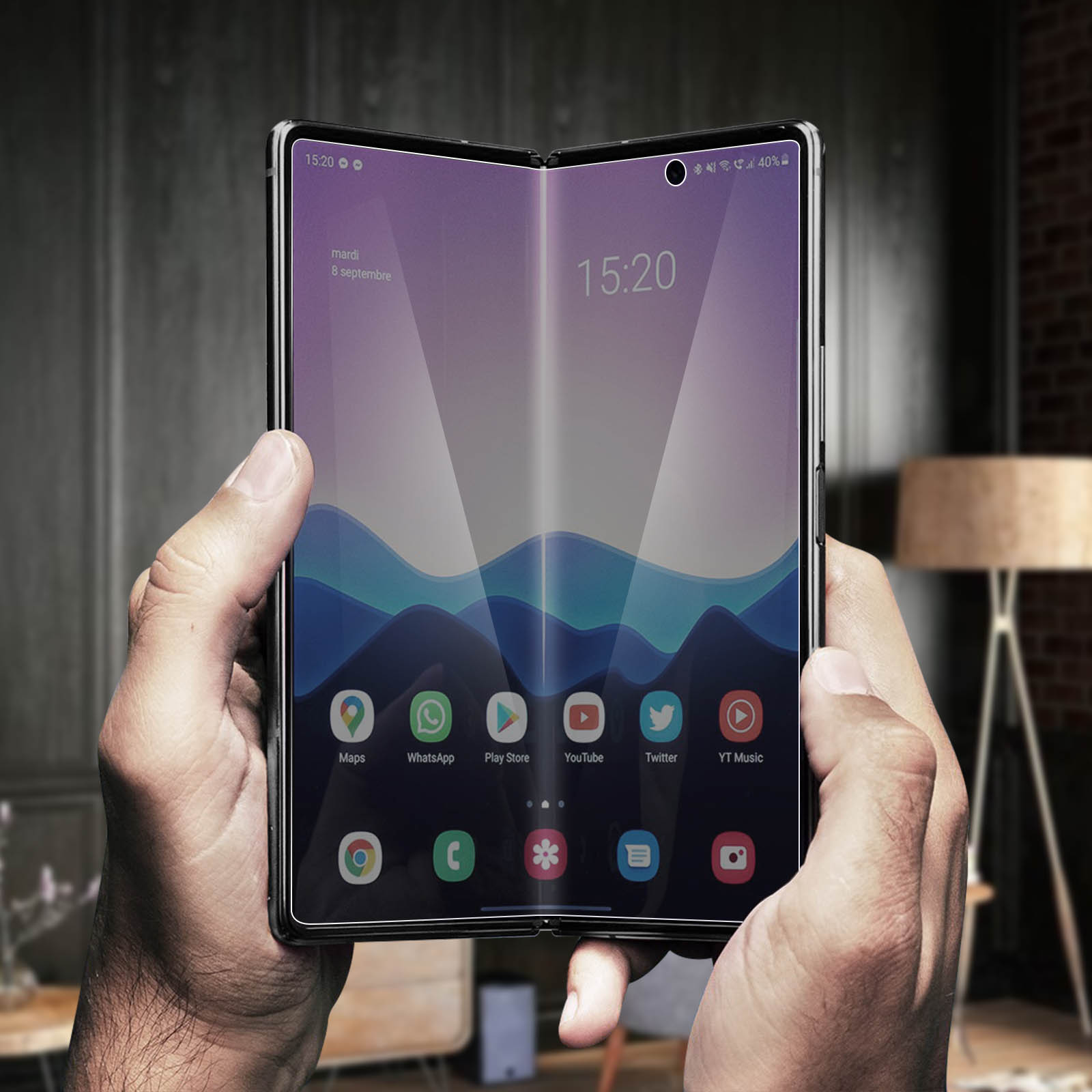 Telefono pieghevole aperto, mostra ora e app. Tenuto in mano su sfondo sfocato. Lo schermo mostra l'ora 15:20.