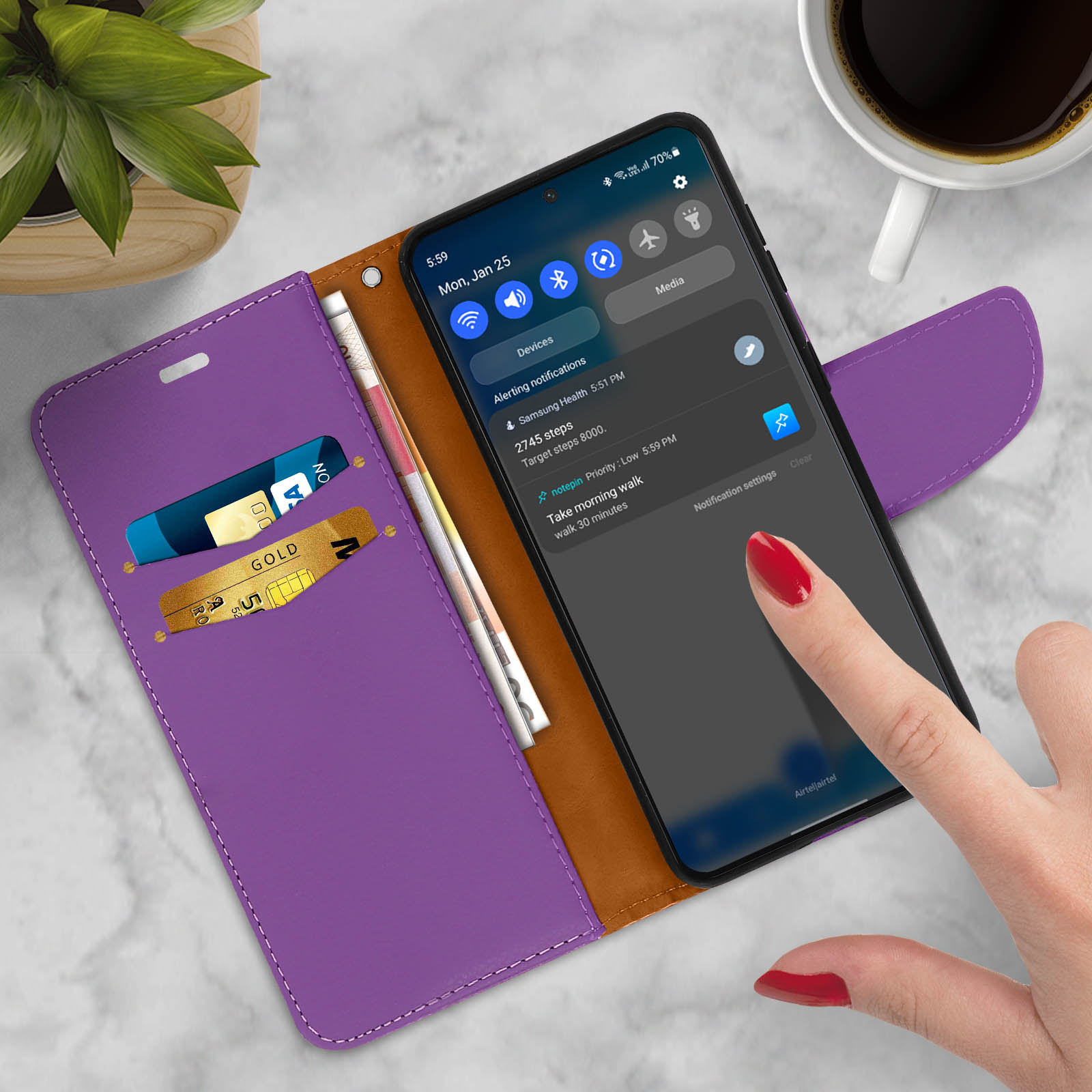 Custodia per telefono viola aperta, rivelando un telefono con schermo acceso. Carte e denaro nella custodia.