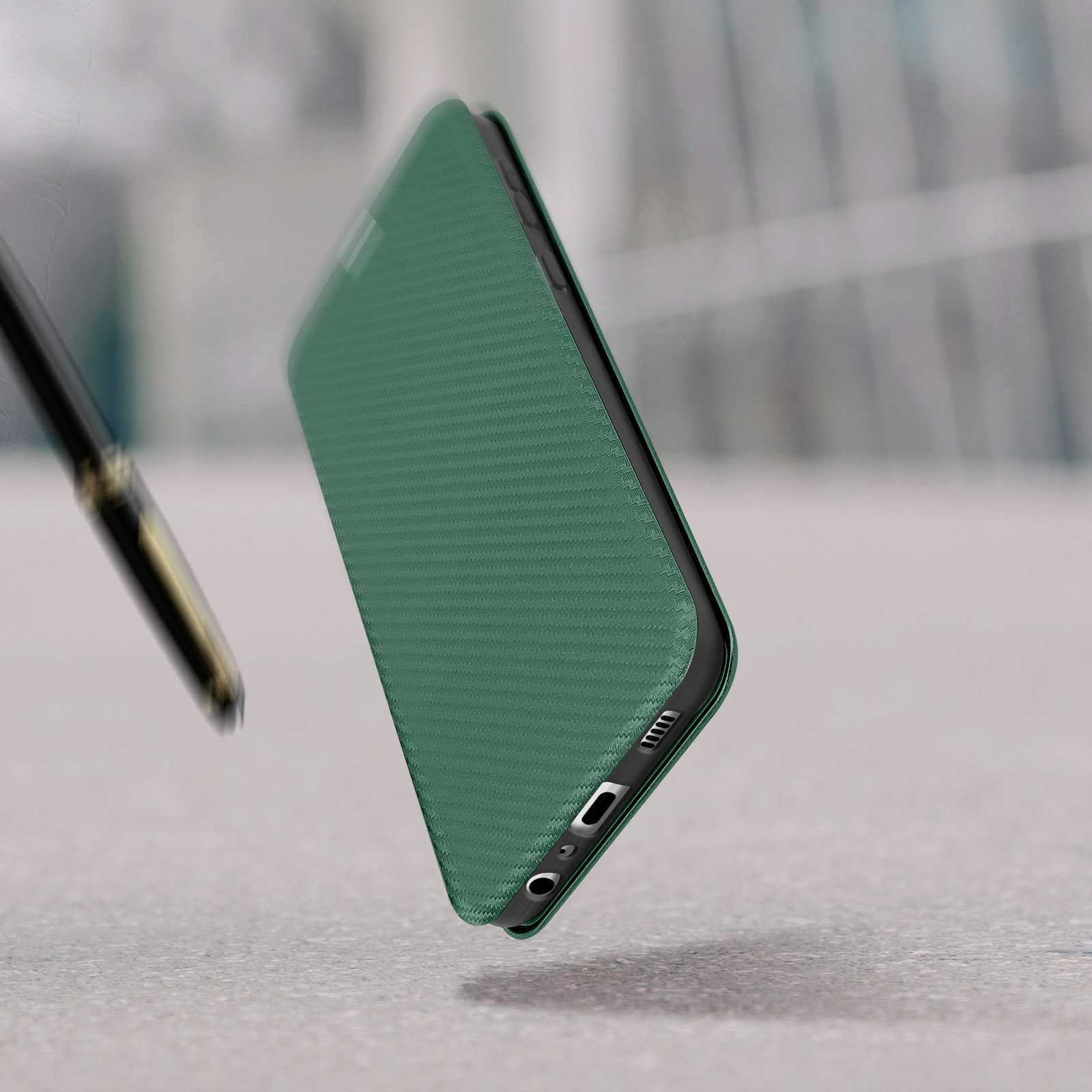 Een groene telefoonhoes, gesloten, schuin, op een oppervlak. Een pen valt.