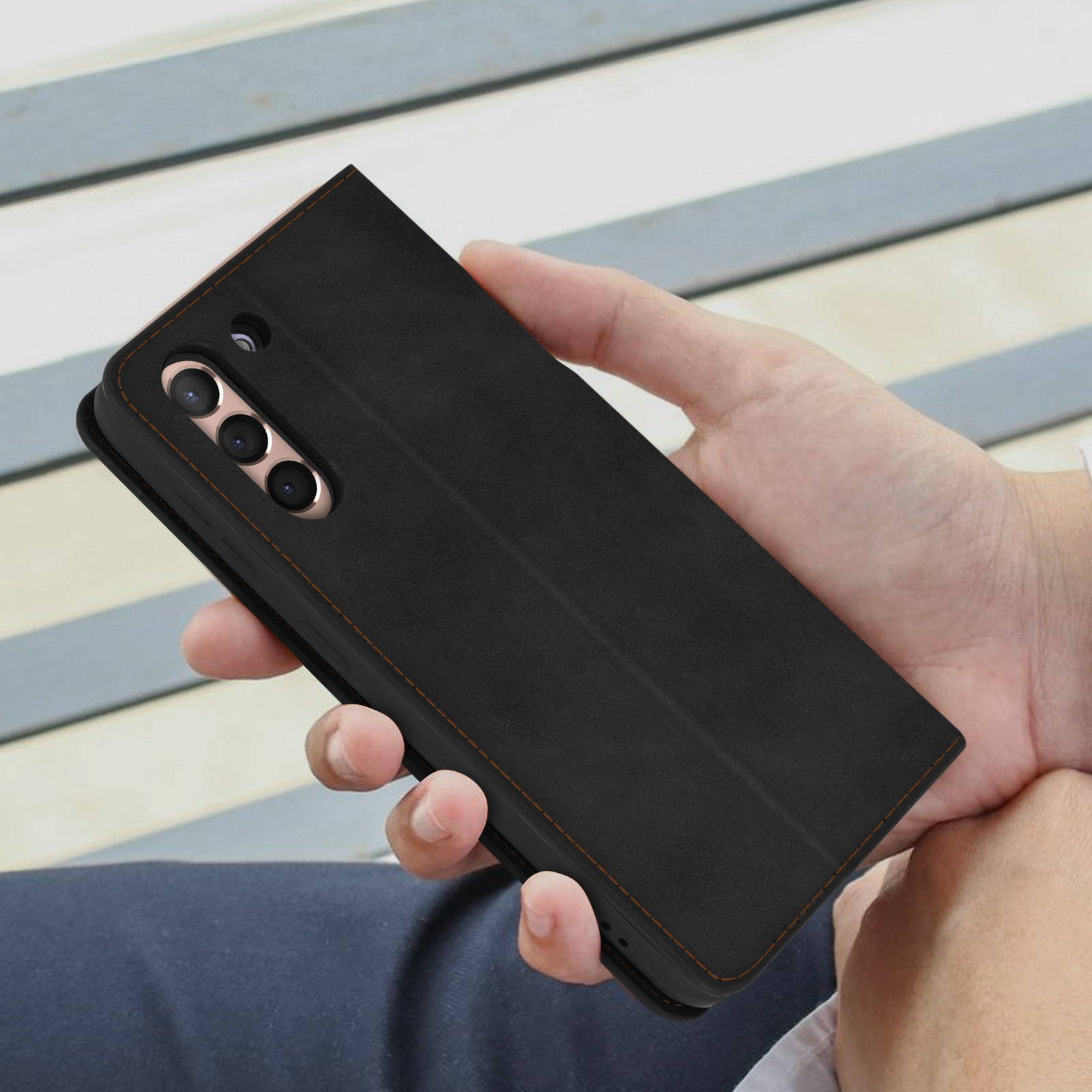 Un telefono nero in una custodia, tenuto in mano, che mostra il retro.