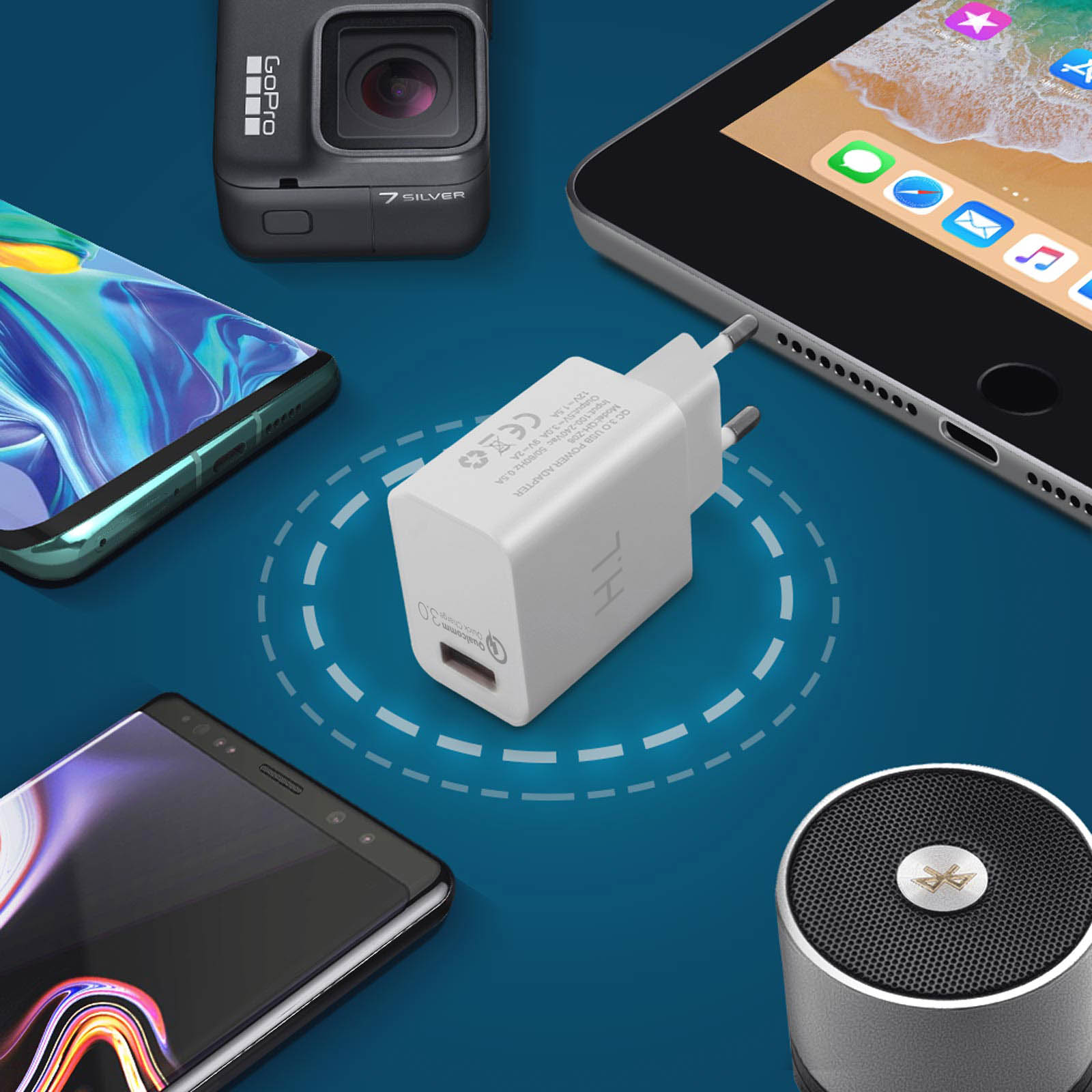 Verschiedene Gadgets: Ladegerät, Telefon, Tablet, GoPro und Lautsprecher auf blauer Oberfläche.
