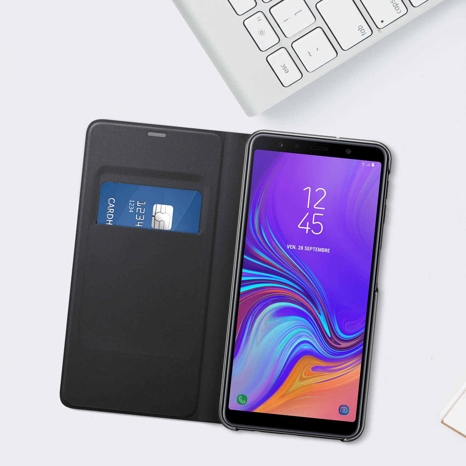 Teléfono en funda negra, mostrando la hora. Tarjeta de crédito en la funda. Fondo blanco.