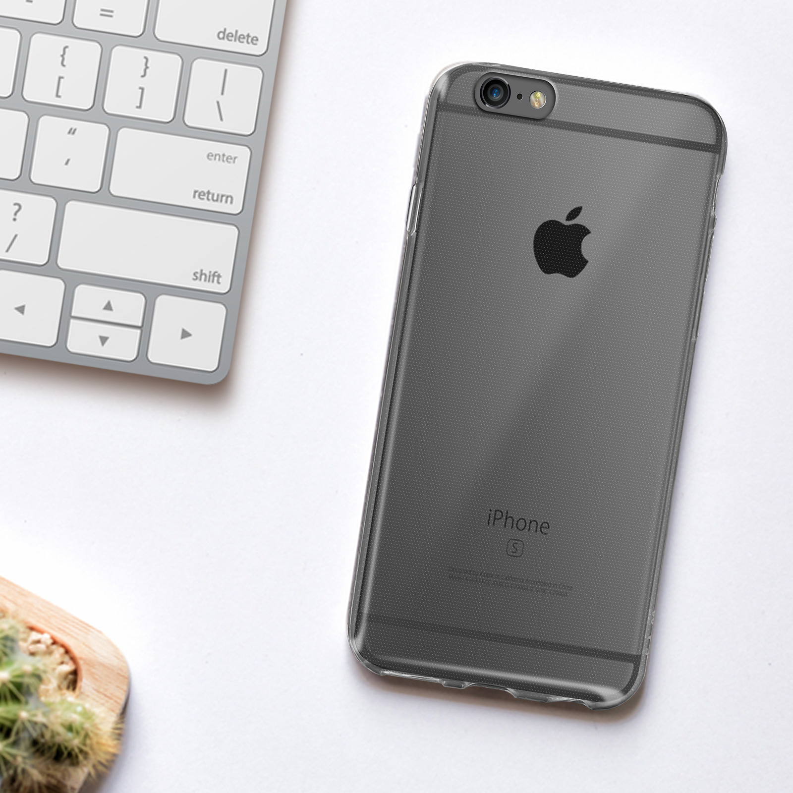 iPhone negro en una funda transparente, sobre un escritorio blanco junto a un teclado y un cactus.