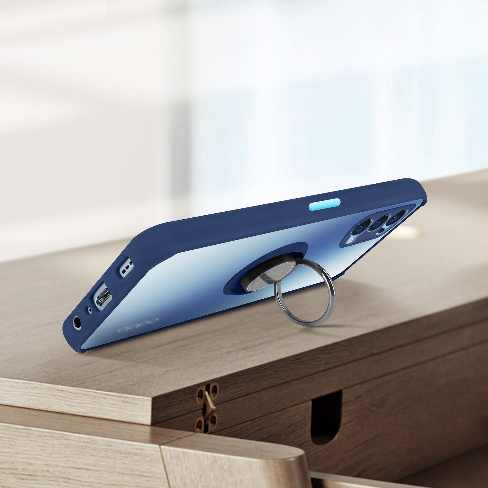 Custodia blu per telefono con un supporto ad anello su un tavolo. Il telefono è appoggiato a una scrivania. Lo sfondo è sfocato.