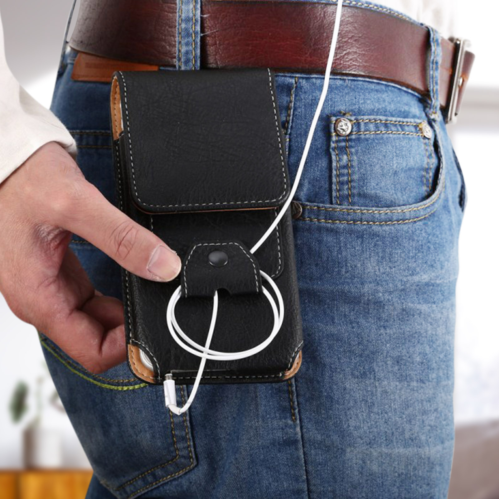 Una persona che tiene una custodia per telefono con auricolari collegati. La custodia e il telefono sono su jeans.