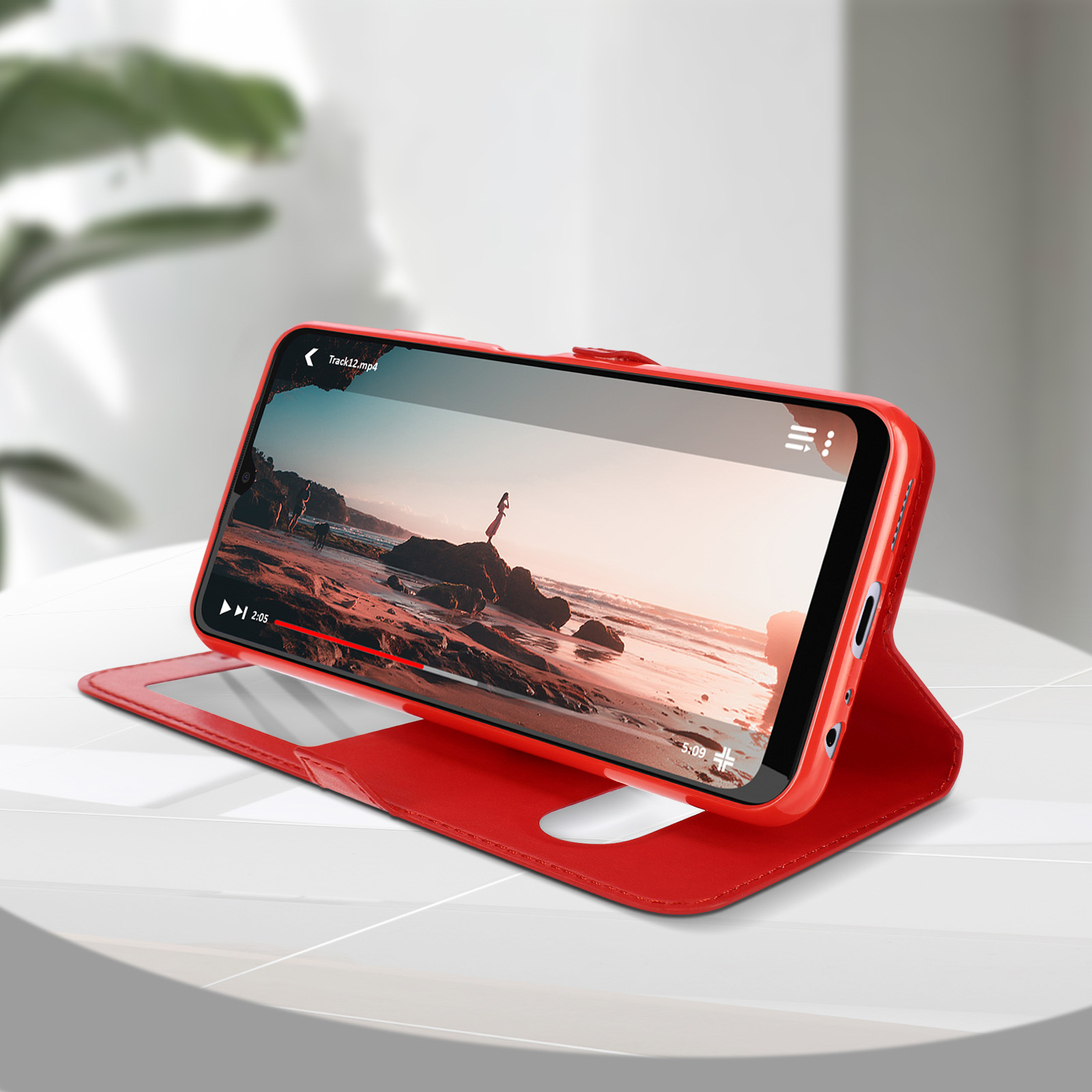 Coque de téléphone rouge ouverte avec un téléphone diffusant une vidéo. L'écran montre une scène de plage.