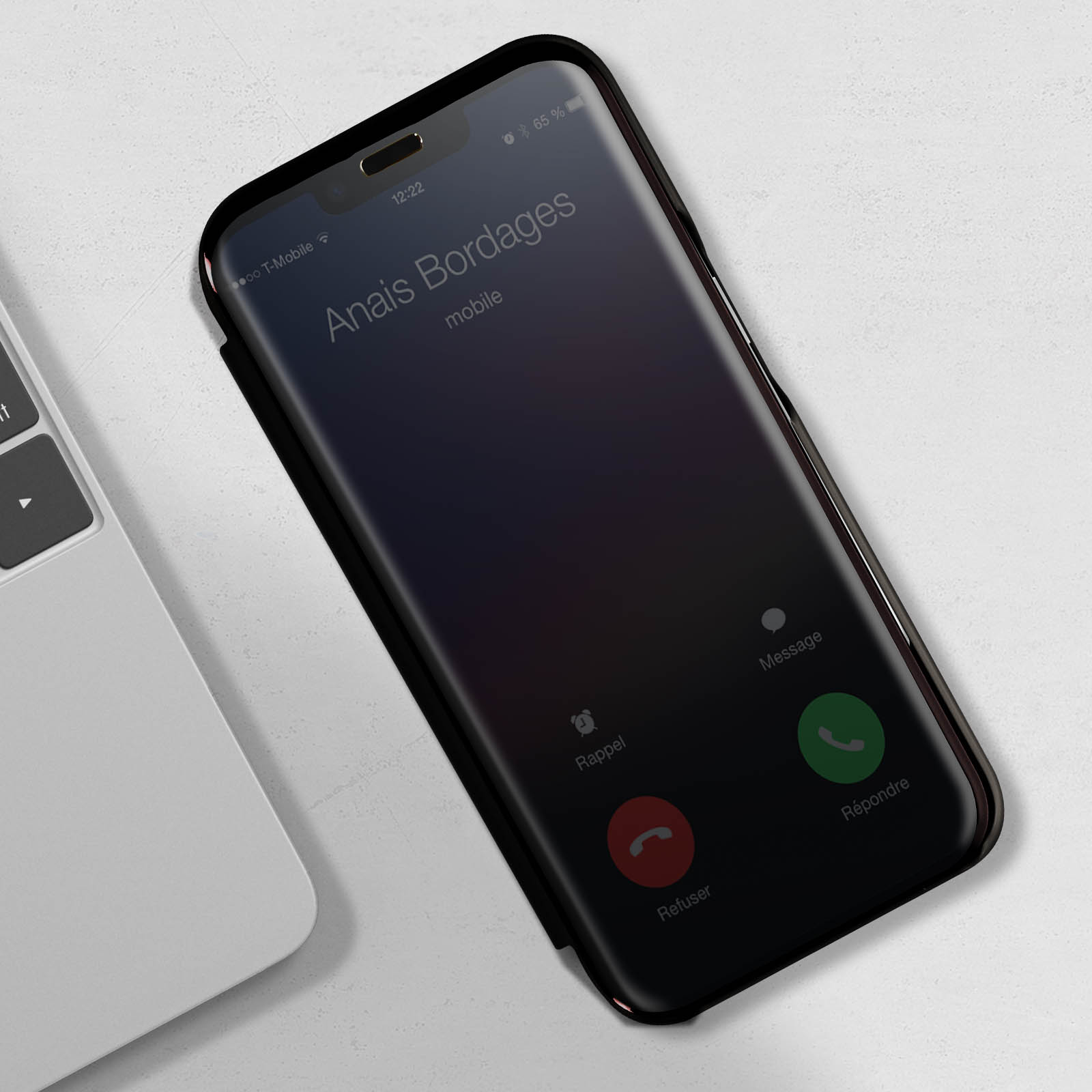 Un telefono che mostra una schermata di chiamata con il nome di un contatto. Un laptop è parzialmente visibile a sinistra.