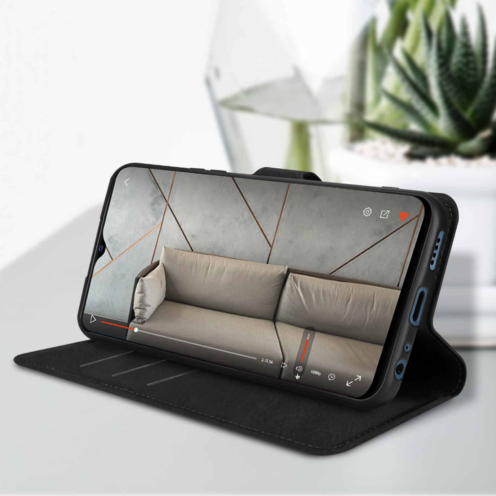 Téléphone dans un étui noir. Le téléphone affiche une vidéo d'un canapé et d'un mur gris clair.