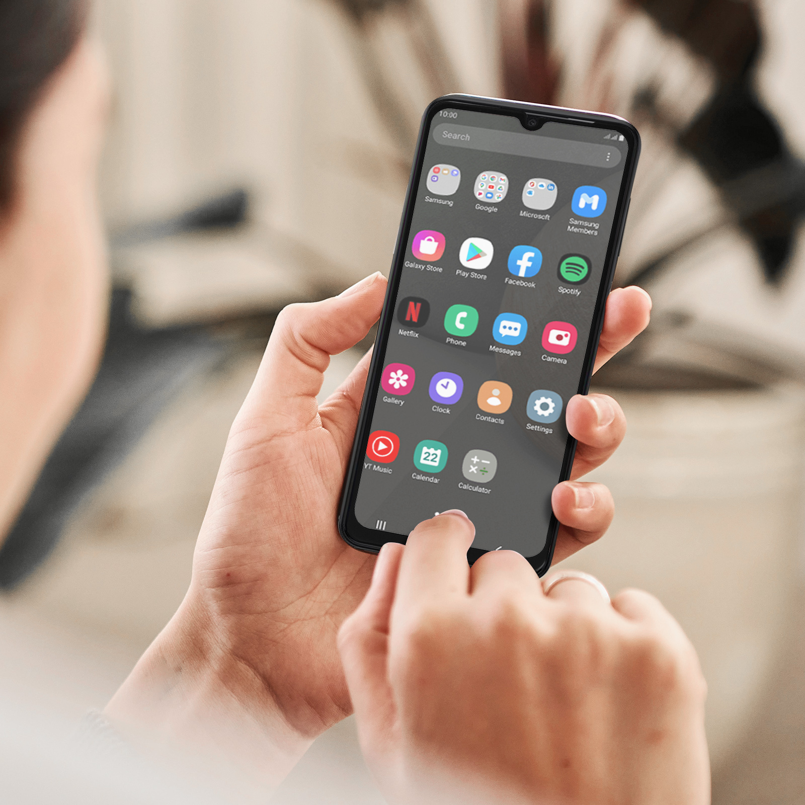 Een persoon houdt een smartphone vast met app-iconen zoals Facebook en Spotify. Een vinger raakt het scherm aan.