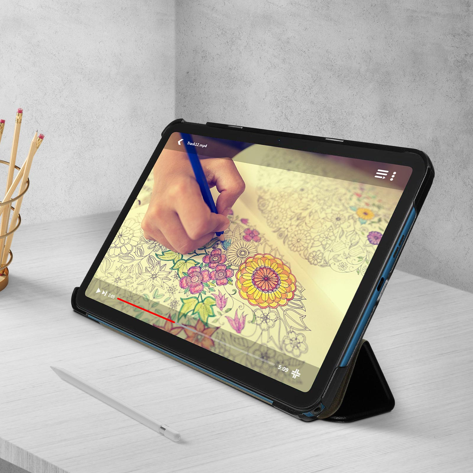 Tablet che riproduce video. Mano che colora. Matita e supporto sulla scrivania. Custodia nera.