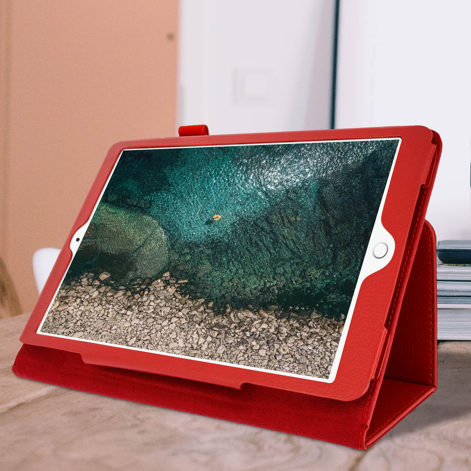 Una custodia rossa per tablet che sorregge un tablet, mostrando una scena di spiaggia sottomarina.