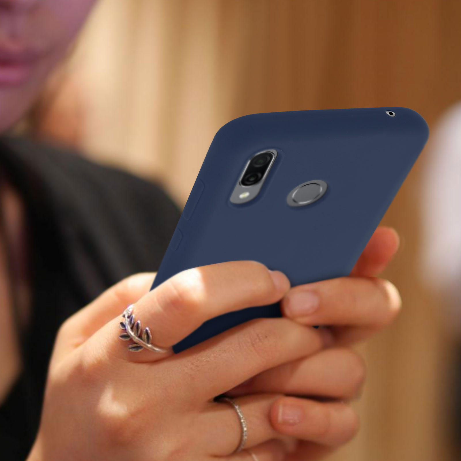 Le mani di una persona che tiene una custodia per telefono blu. Il telefono ha una fotocamera.