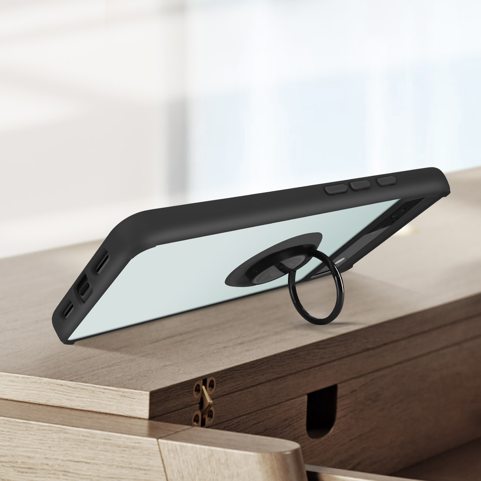 Téléphone avec support de bague, posé sur une surface en bois, l'anneau est visible.