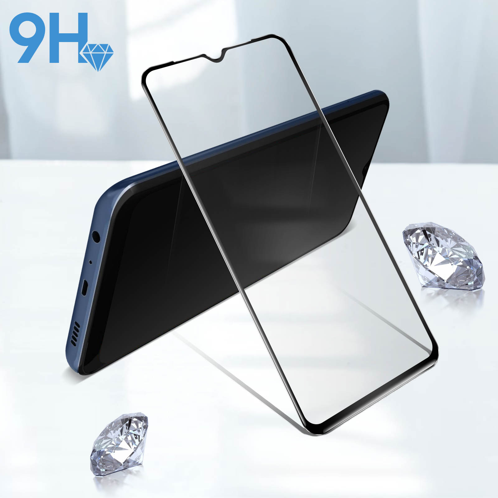 Un telefono con protezione schermo e due diamanti su una superficie bianca.