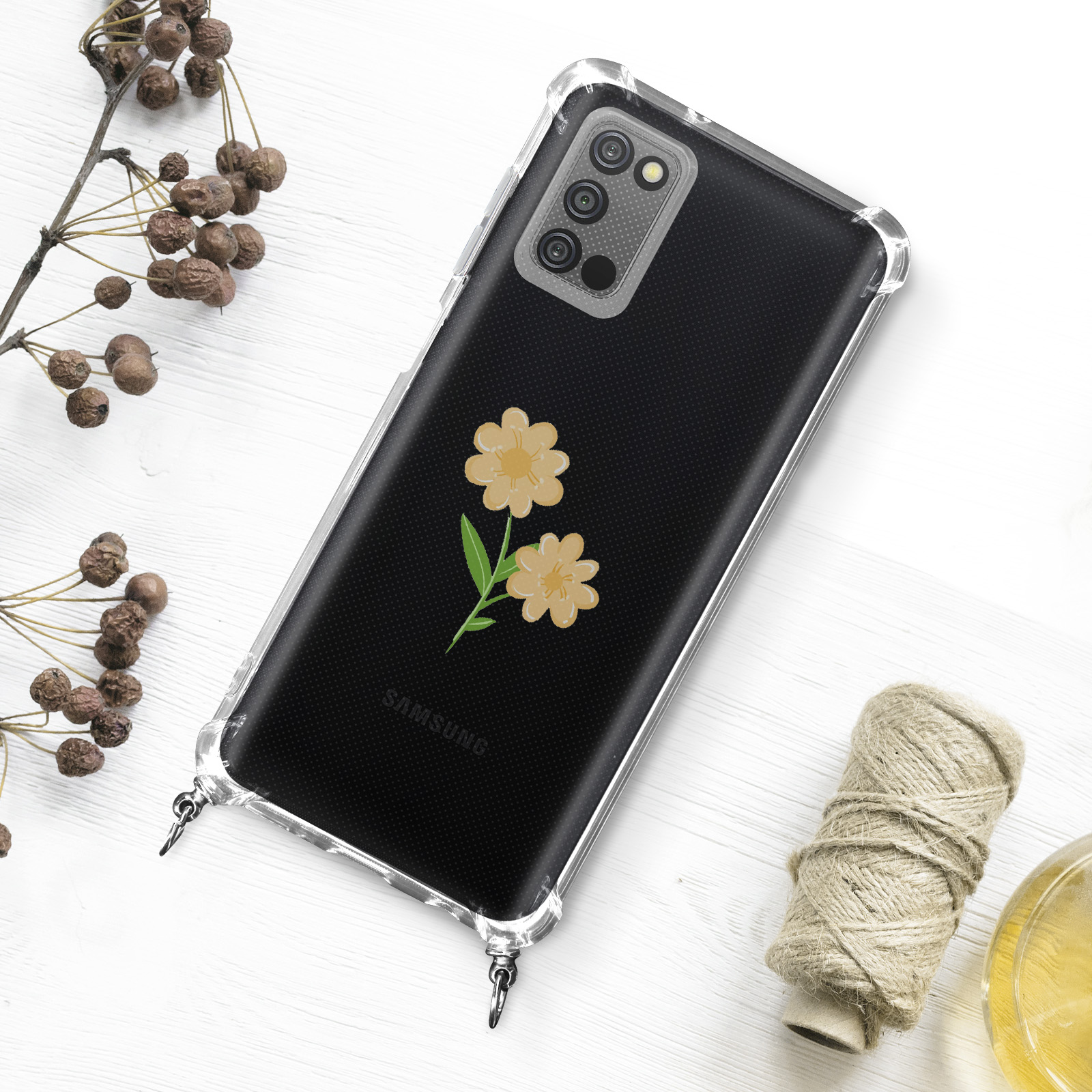 Custodia trasparente con fiori gialli su superficie in legno bianco, con piante secche.