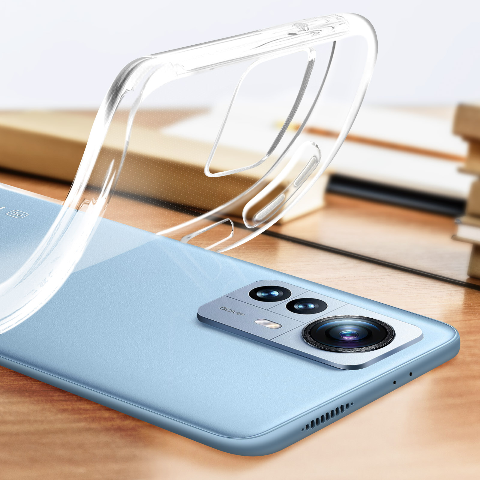 Una custodia trasparente è sopra un telefono azzurro. Libri sullo sfondo.