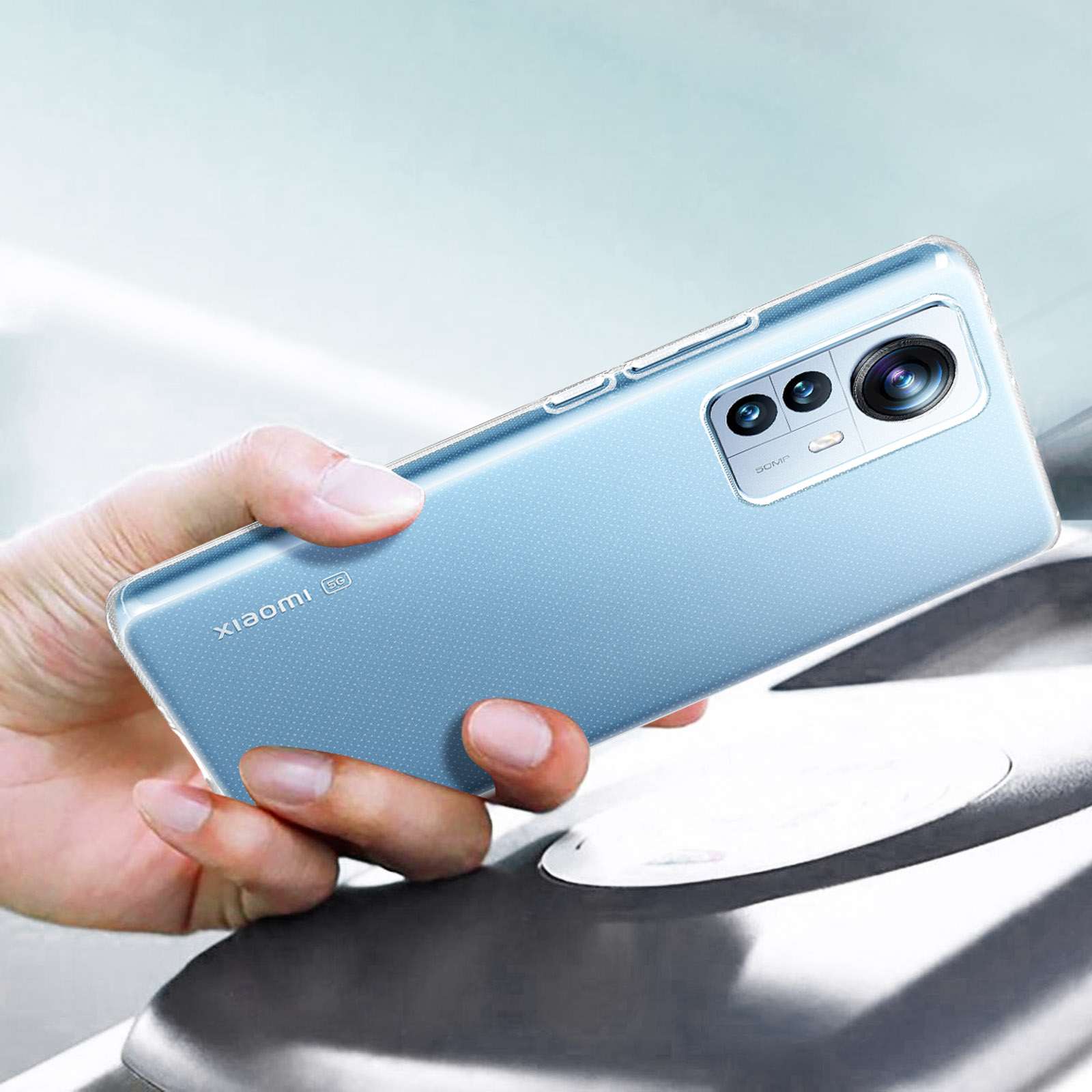 La mano di una persona che tiene un telefono azzurro con una configurazione a tripla fotocamera.