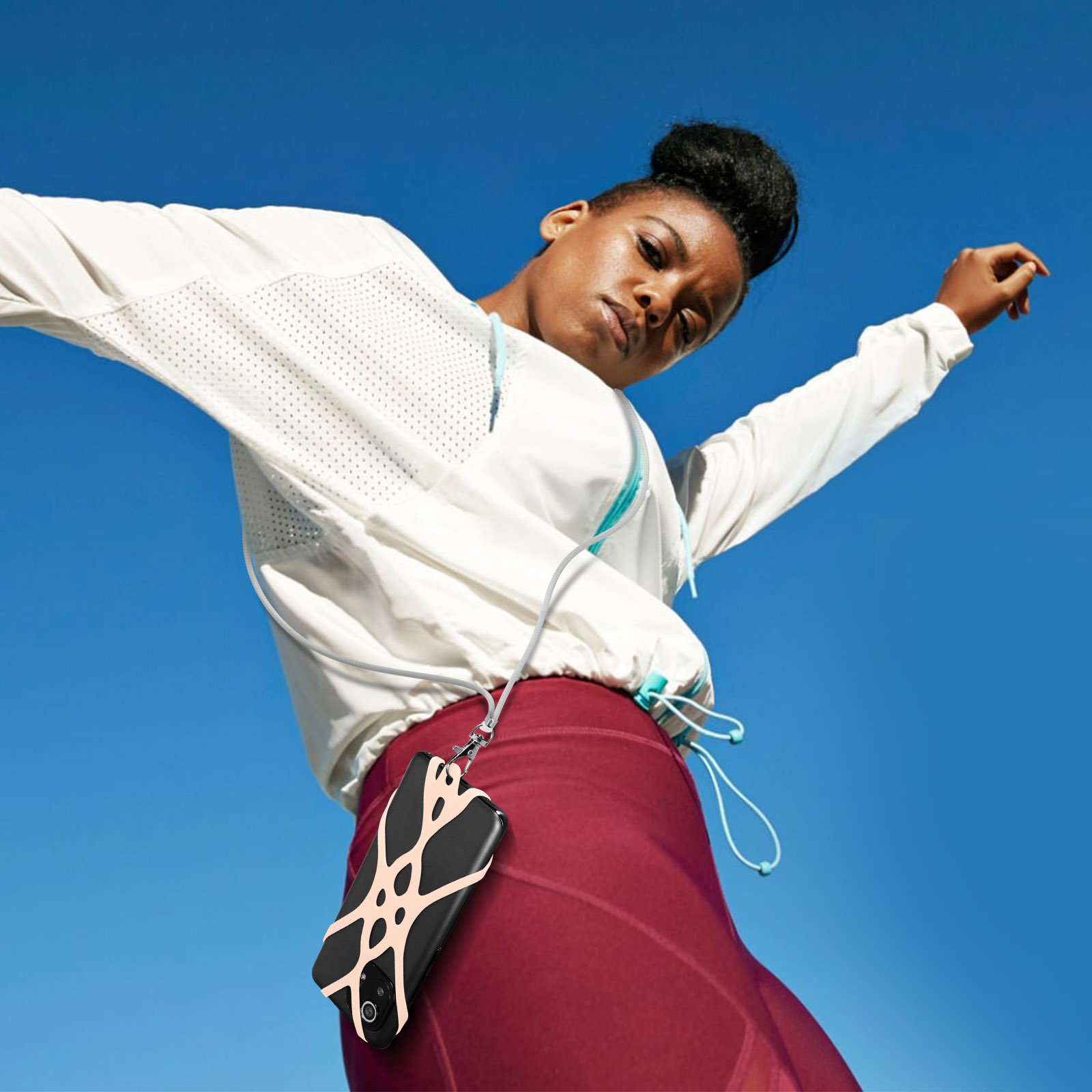 Donna in abbigliamento sportivo con telefono al laccetto cielo blu