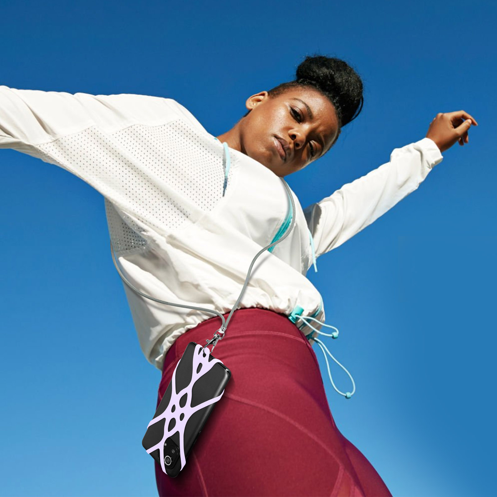 Donna in giacca bianca e leggings bordeaux, con custodia per telefono su laccio.