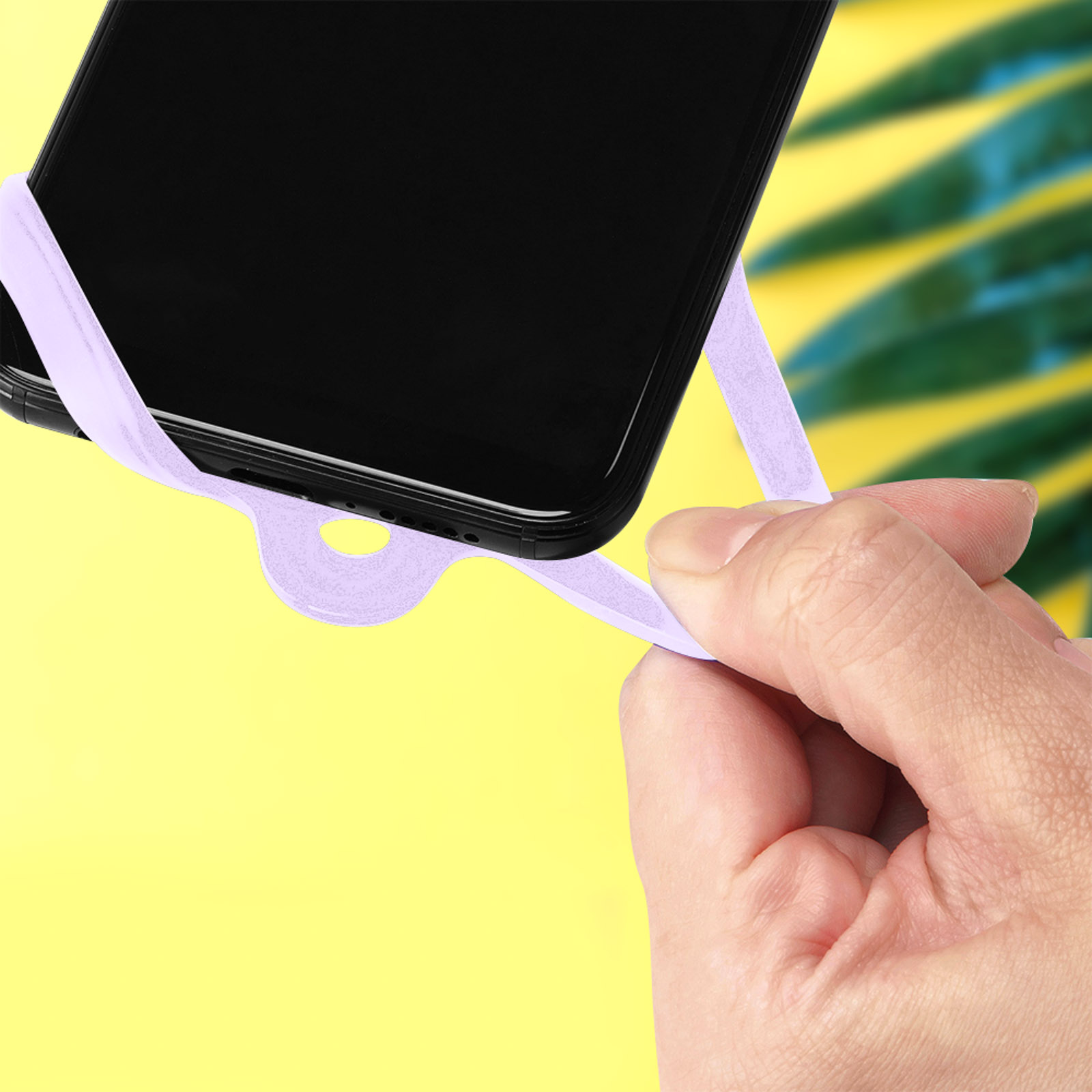 Una mano tiene un cinturino viola attaccato a uno smartphone nero.